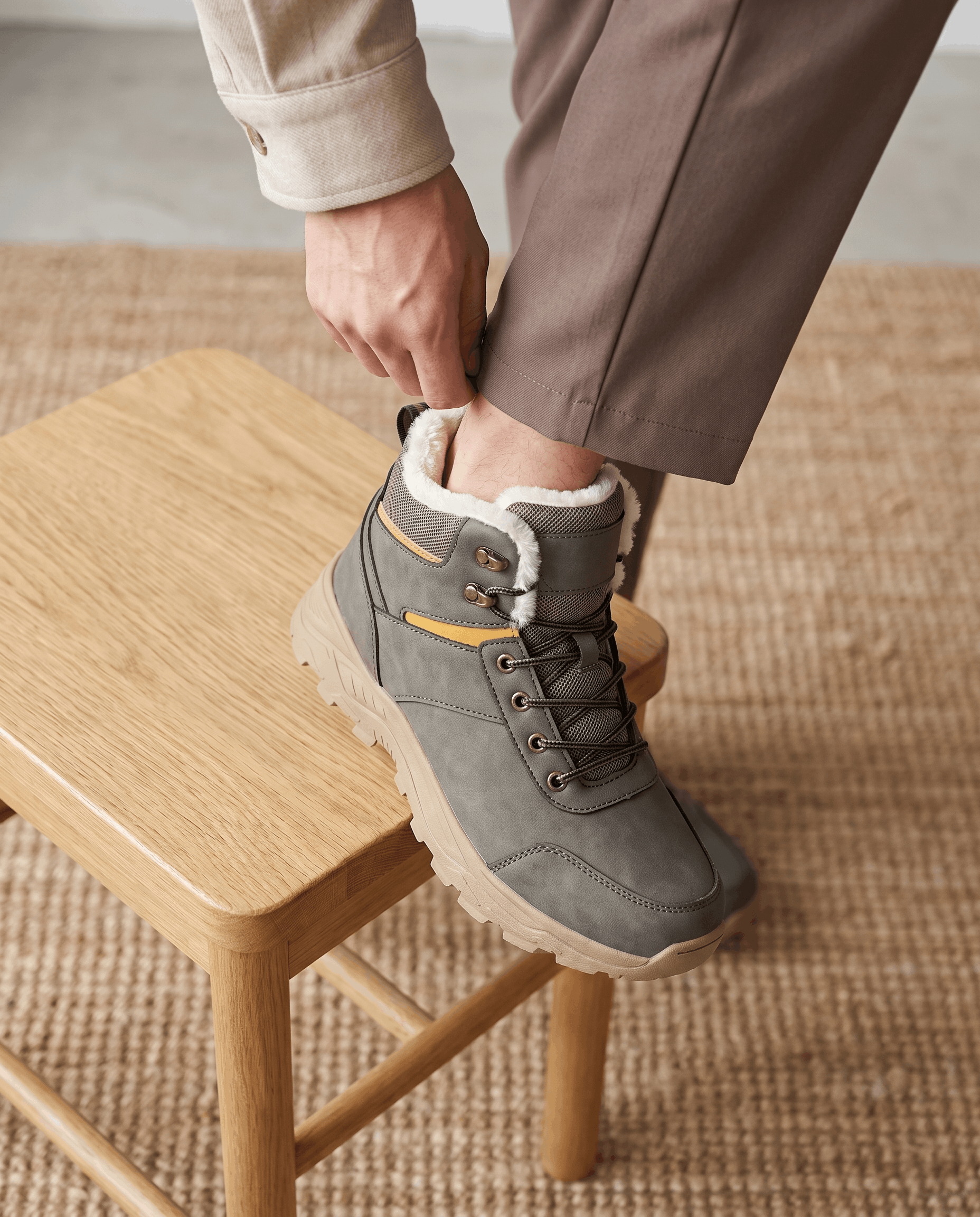 Person wearing gray winter boots while standing on a wooden stool.