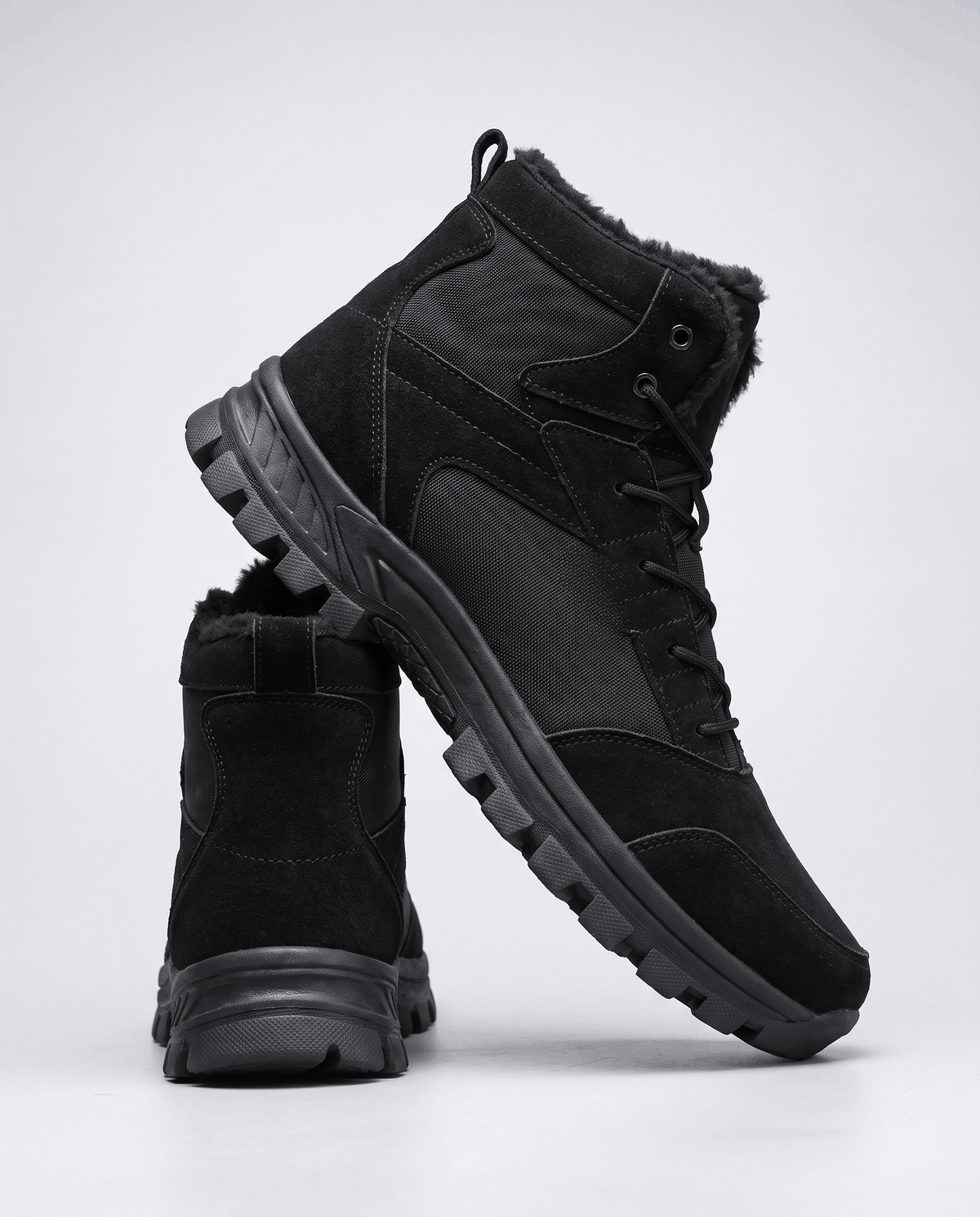 One black boot upright beside another leaning to reveal the lug tread