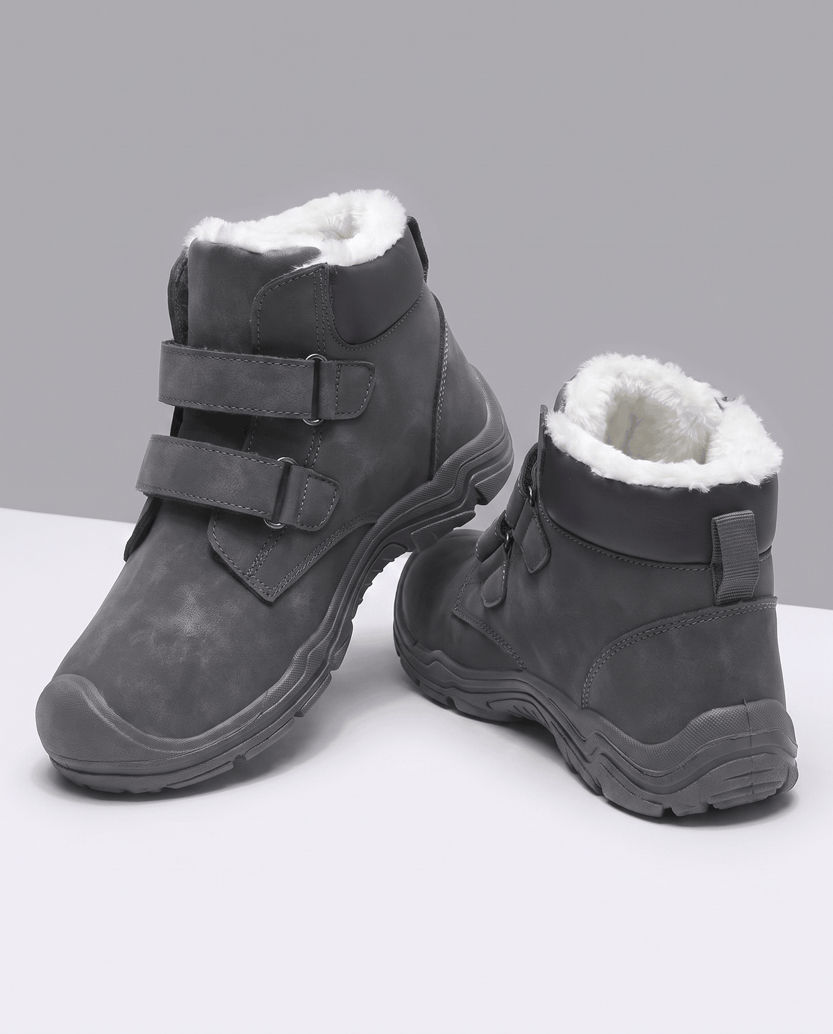 Pair of gray insulated ankle boots displayed on a concrete pedestal.