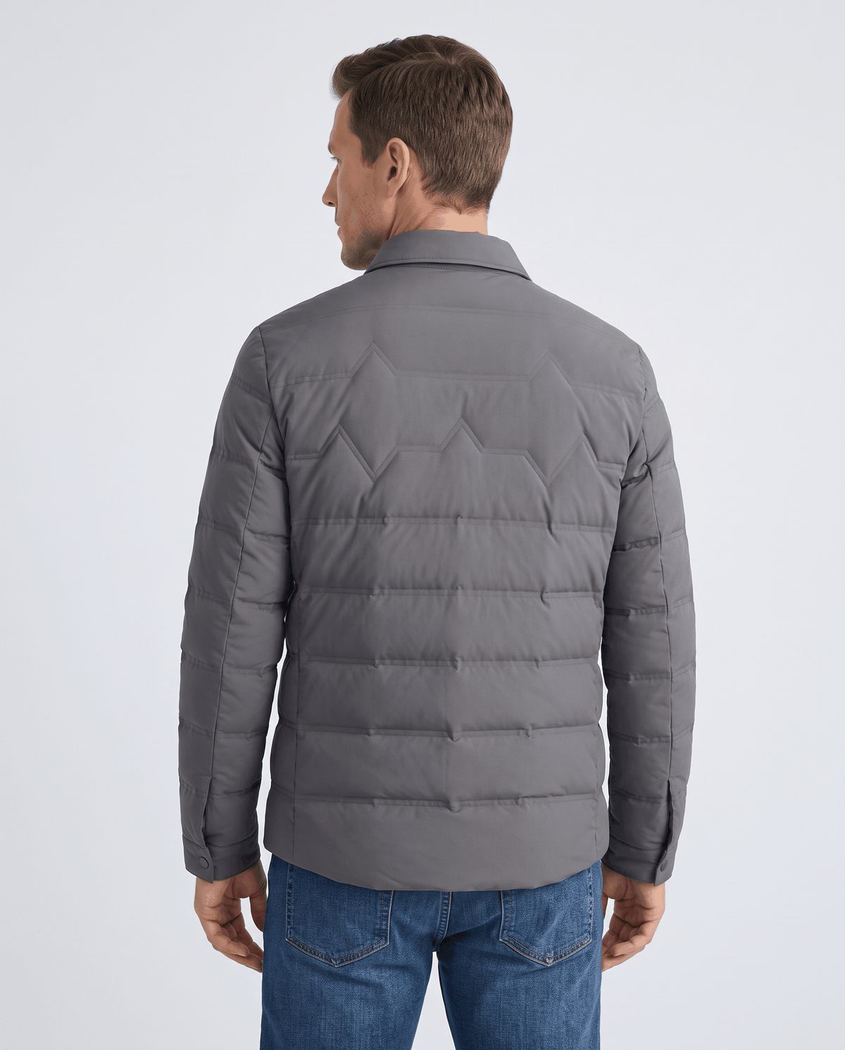 Back view of a man wearing a gray quilted puffer jacket