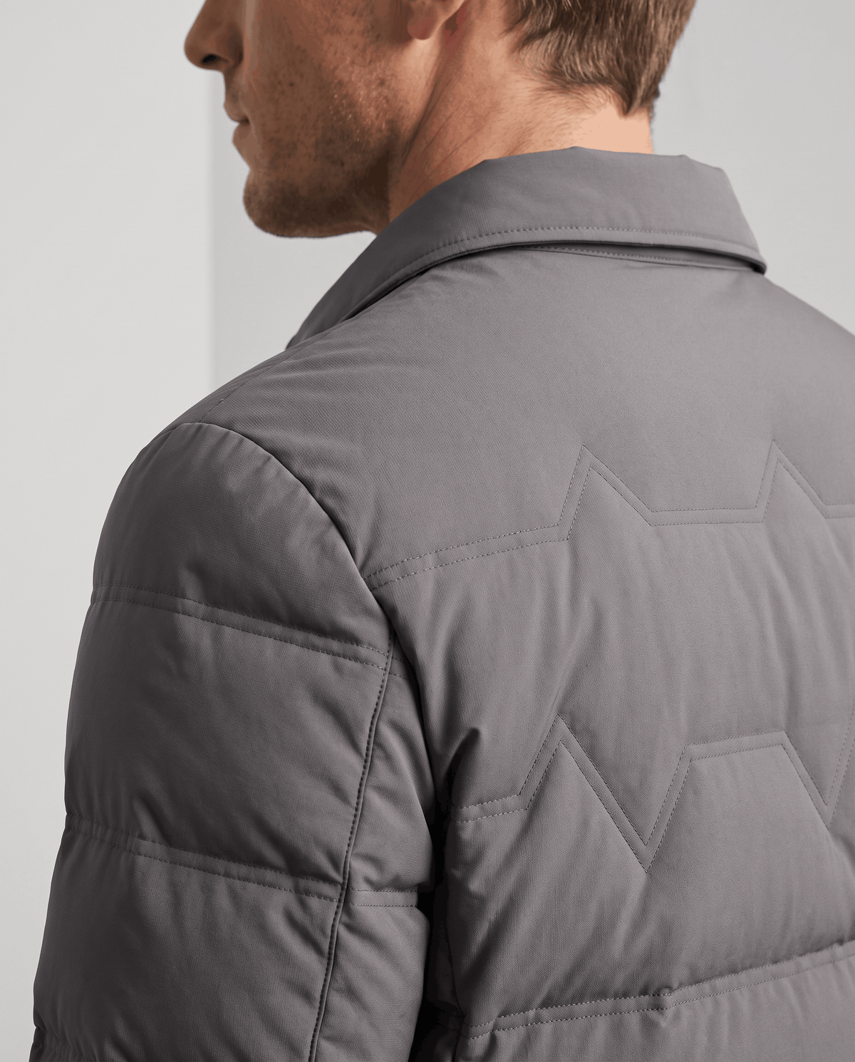 Close-up of the quilted shoulder and sleeve on a gray puffer jacket