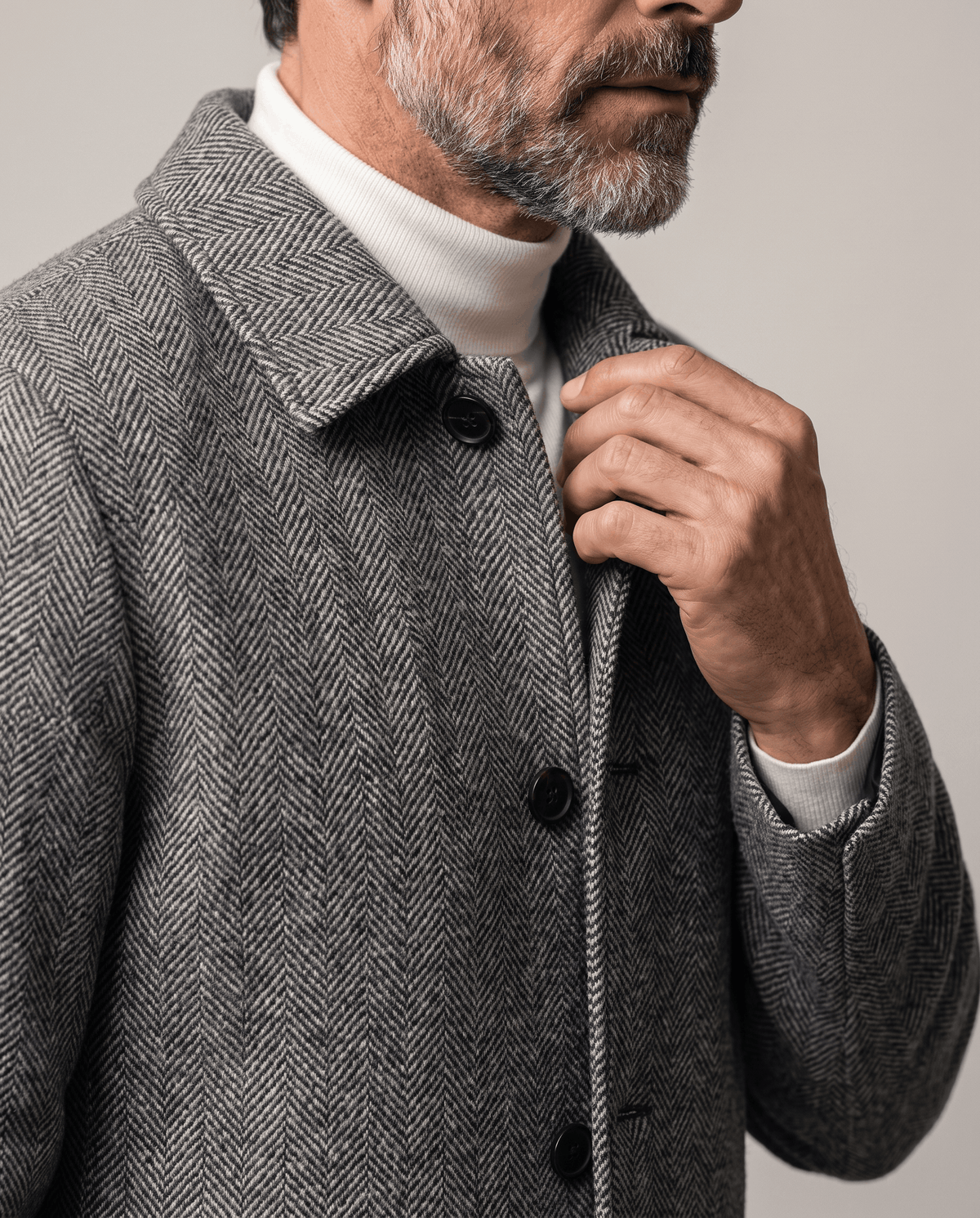 Hand on the button front of the Henrik gray herringbone wool coat