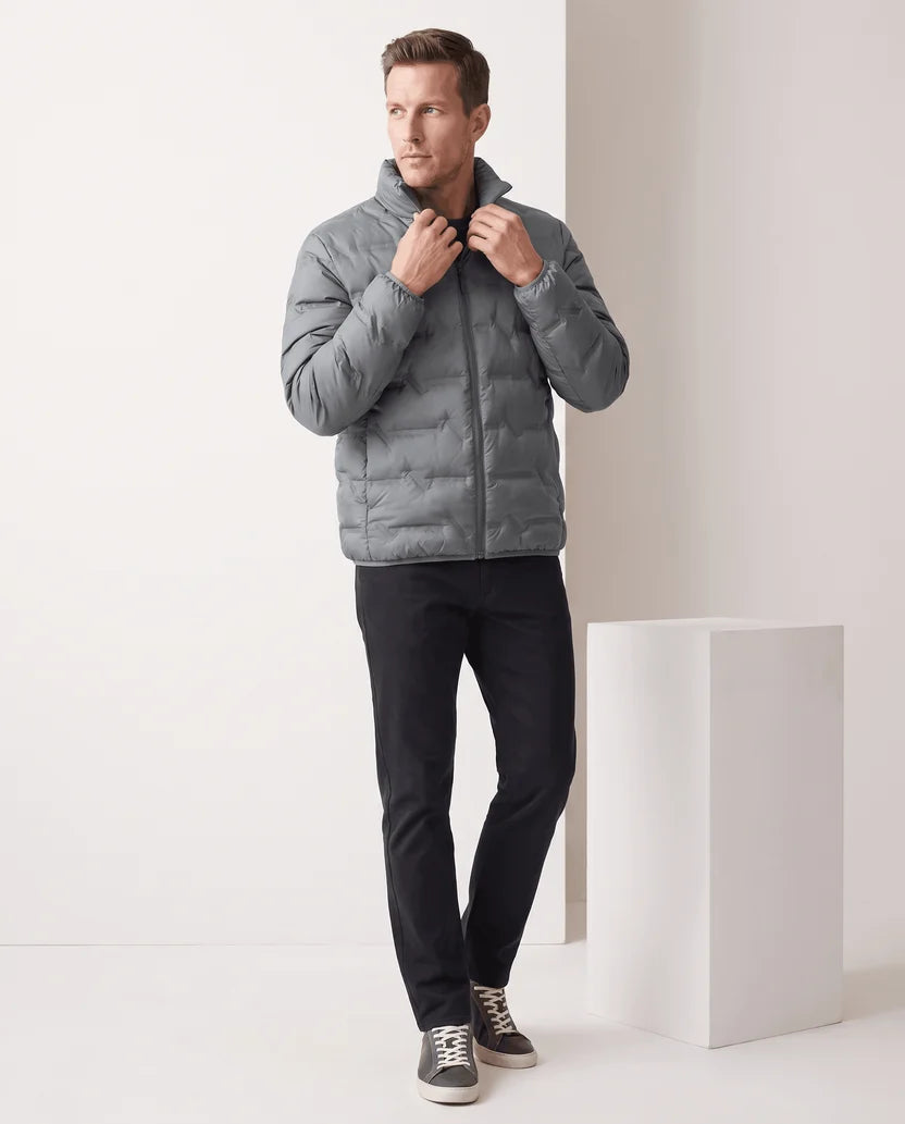 Man standing in a gray quilted puffer jacket with dark trousers, full-length view