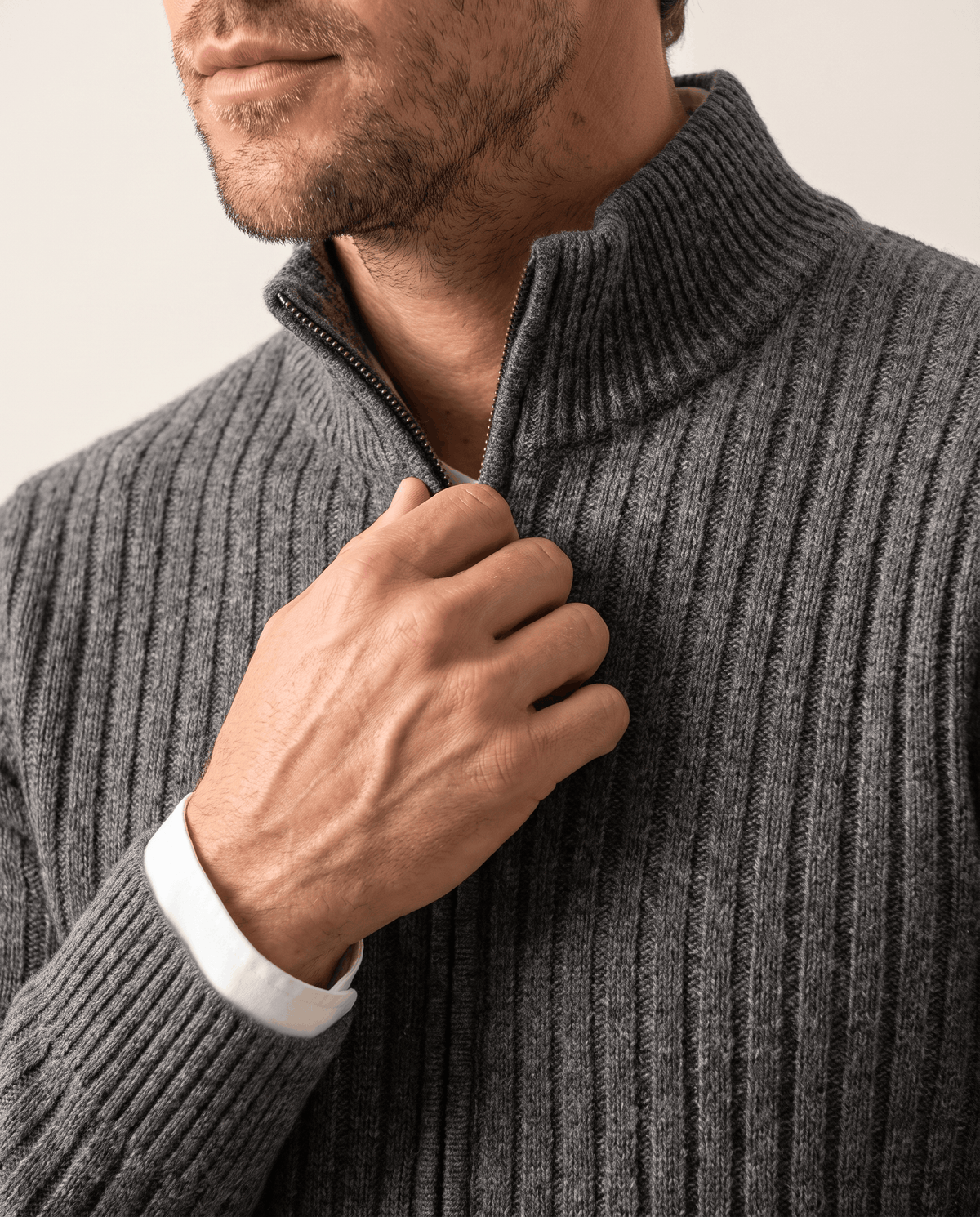 Hand on the zip of the Julian gray wool knit cardigan, showing the ribbed collar