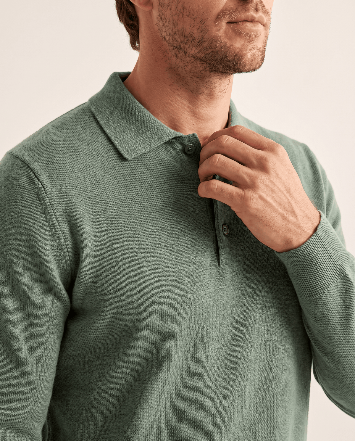Hand on the button placket of the Elias green wool knit polo sweater