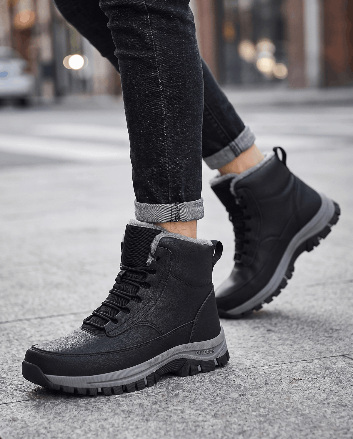 Black boots worn with dark jeans on wet pavement, laces tied
