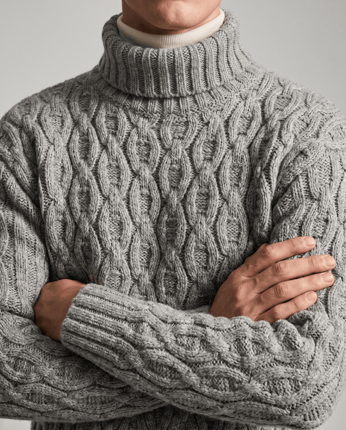 Light gray honeycomb knit front worn over cream underlayer with arms folded