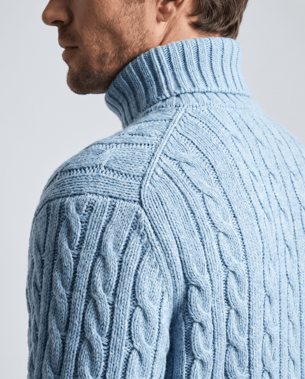 Side view of light blue ribbed turtleneck collar and shoulder cable detail