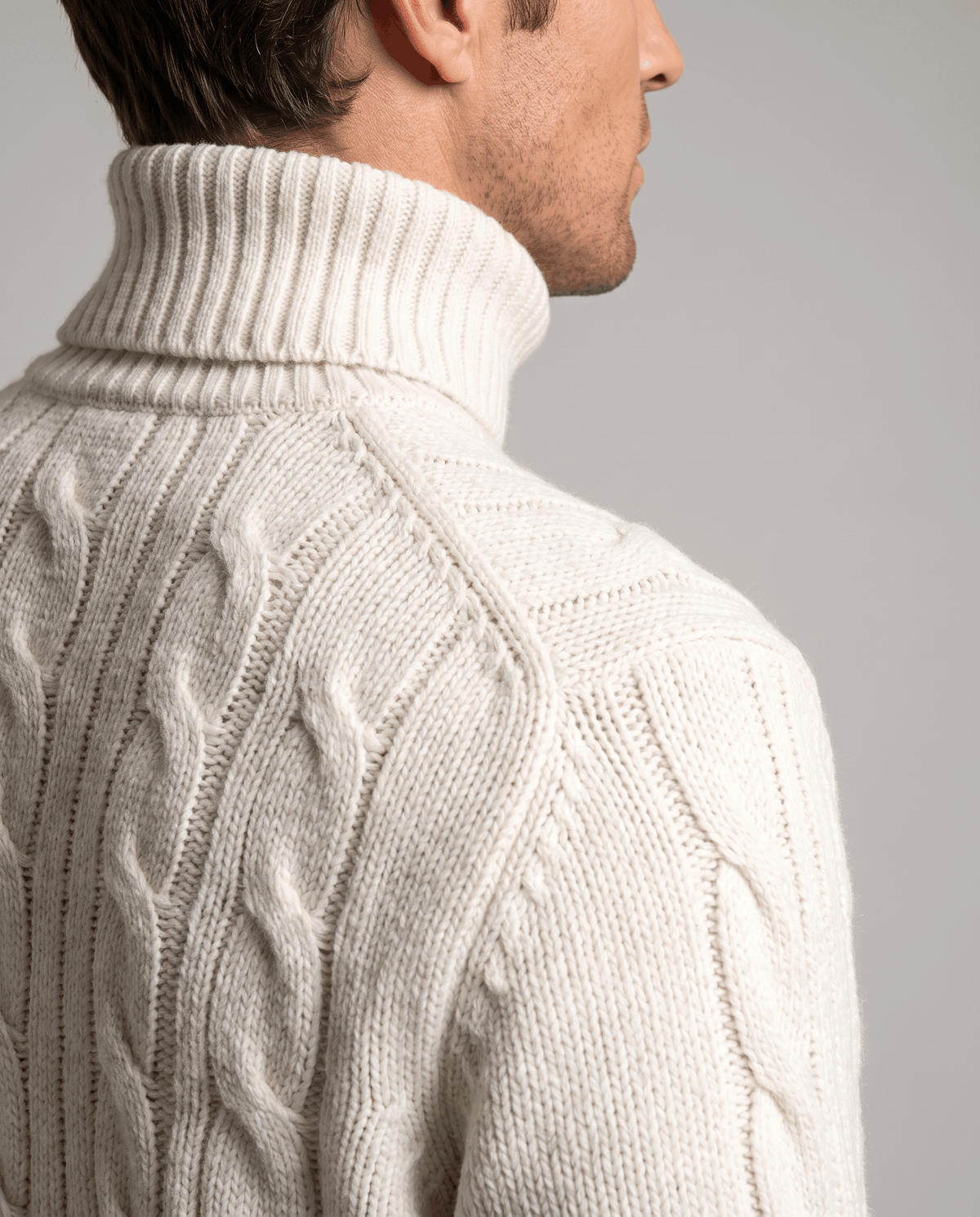 Side profile of white ribbed turtleneck collar and raglan shoulder seam