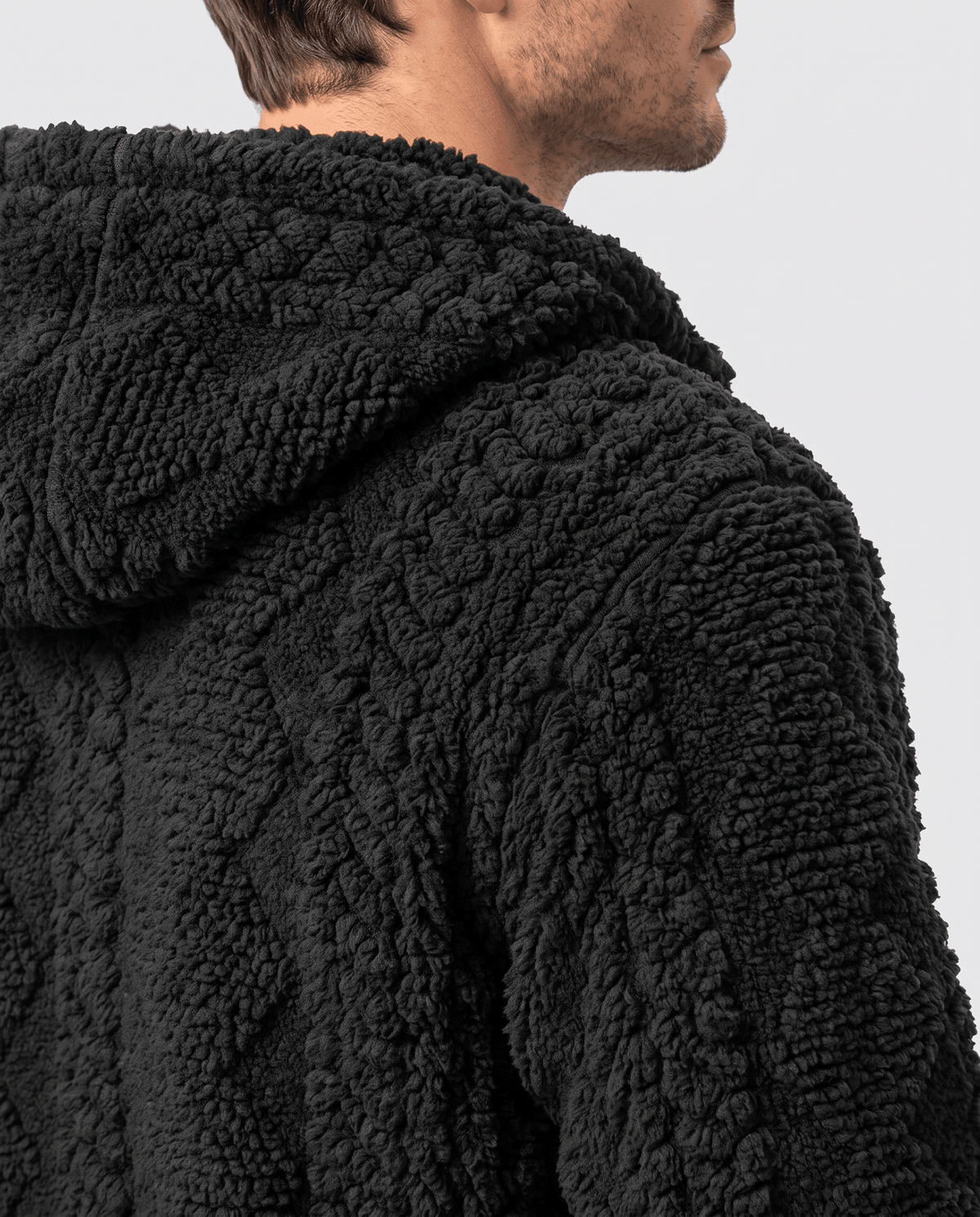 Close-up of black jacket hood and upper back showing the cable-knit pattern