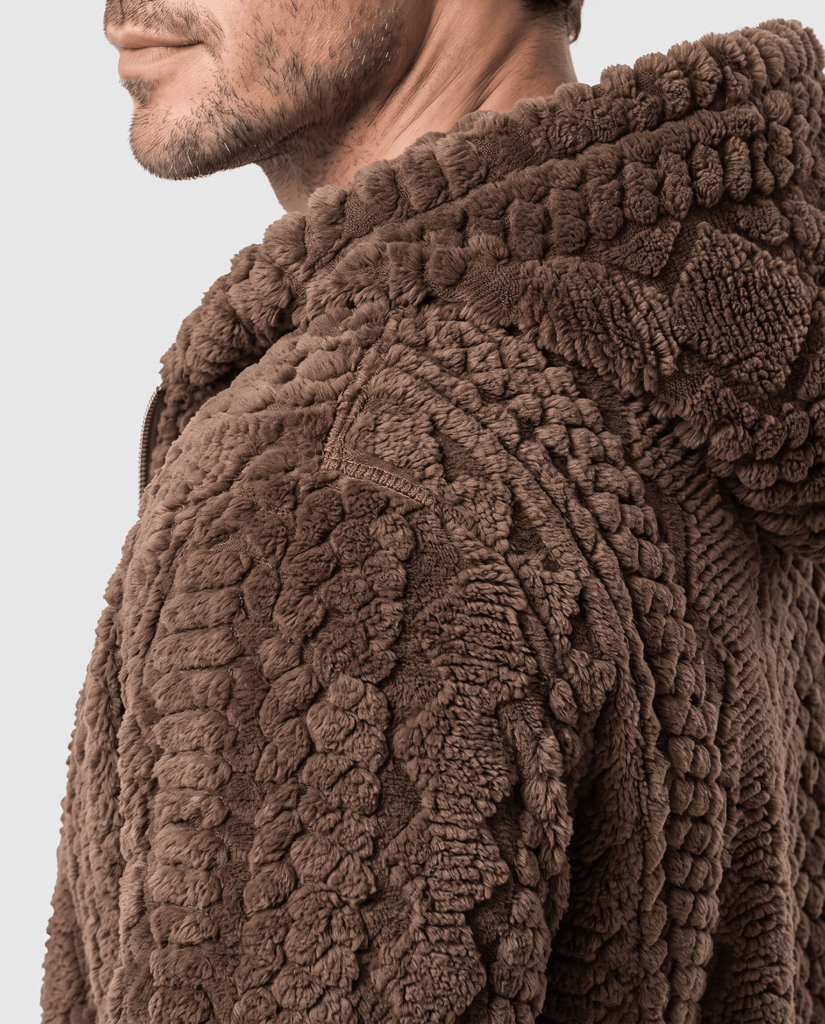 Side close-up of dark brown jacket hood and cable-knit shoulder texture