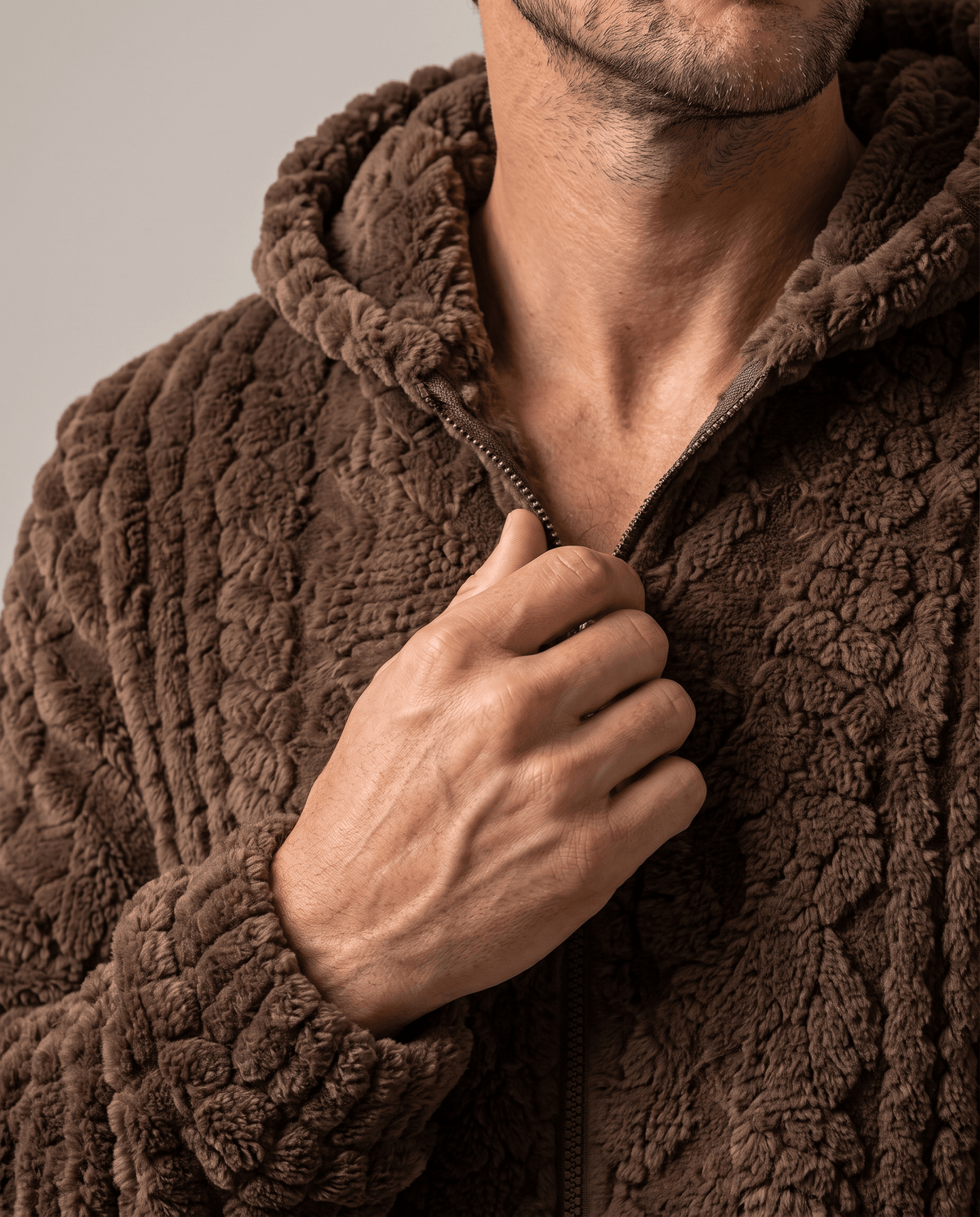 Close-up of dark brown jacket zip and collar with a hand on the zip pull