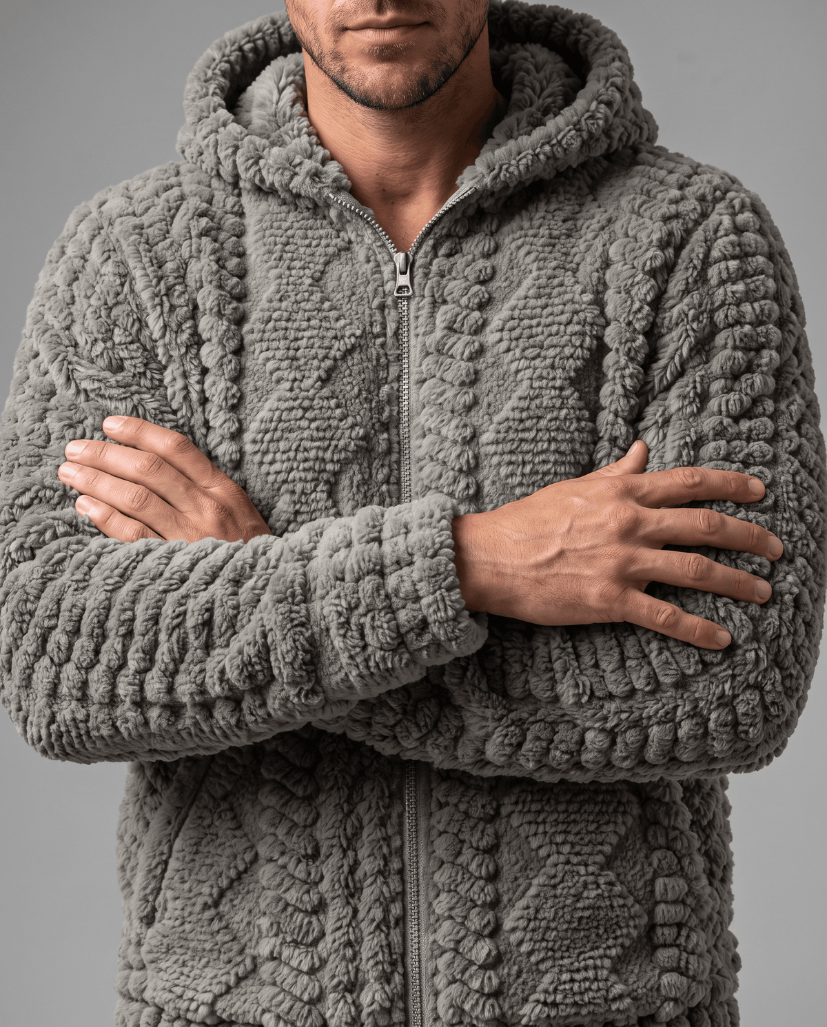 Gray jacket zipped up with arms crossed, showing the chunky cable pattern at the front