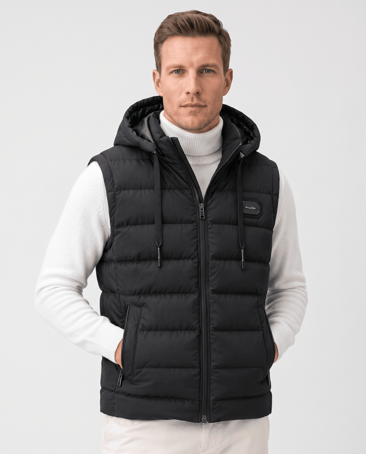 Black hooded quilted vest over a white turtleneck, hands in the front zip pockets