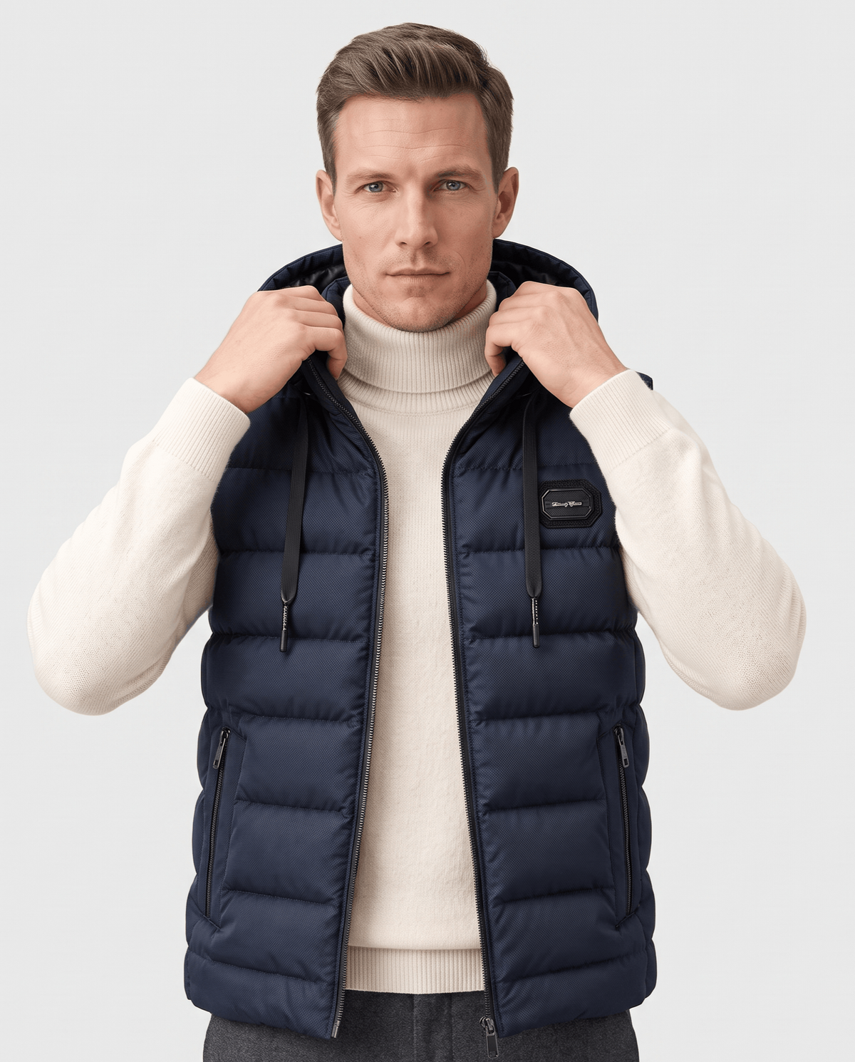 Navy hooded quilted vest over a cream sweater, hood resting back with drawstrings visible