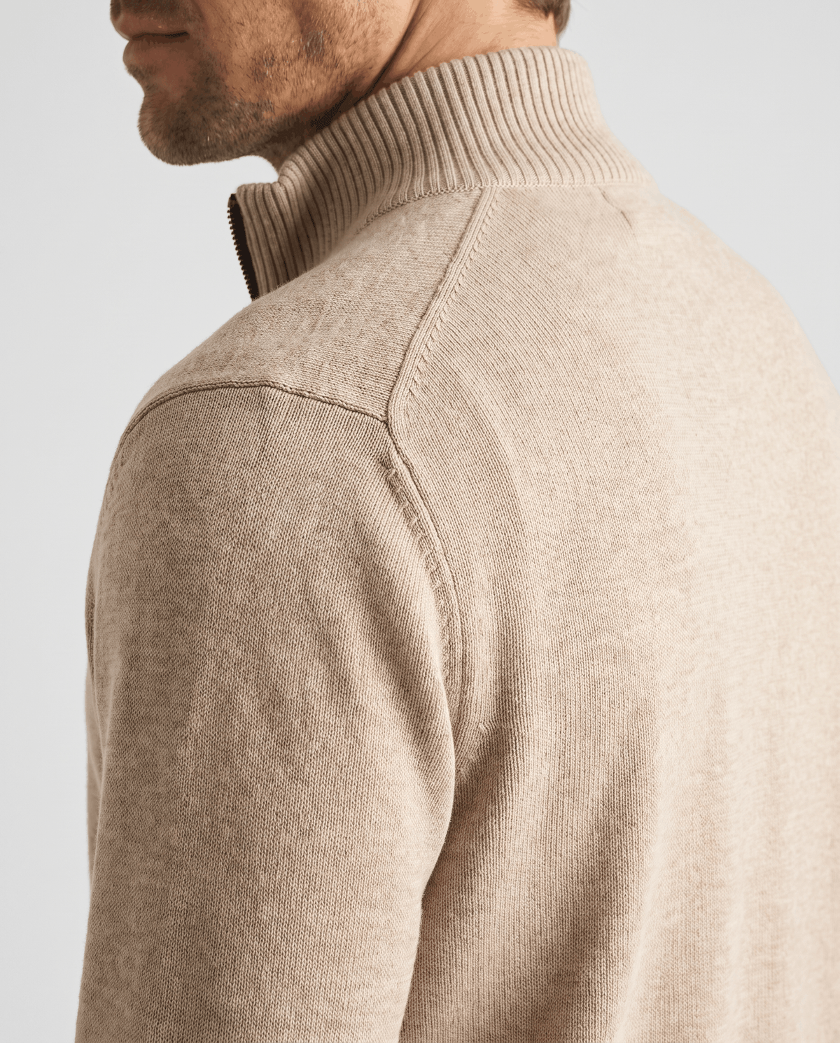 Side close-up of the beige ribbed stand collar and textured shoulder knit