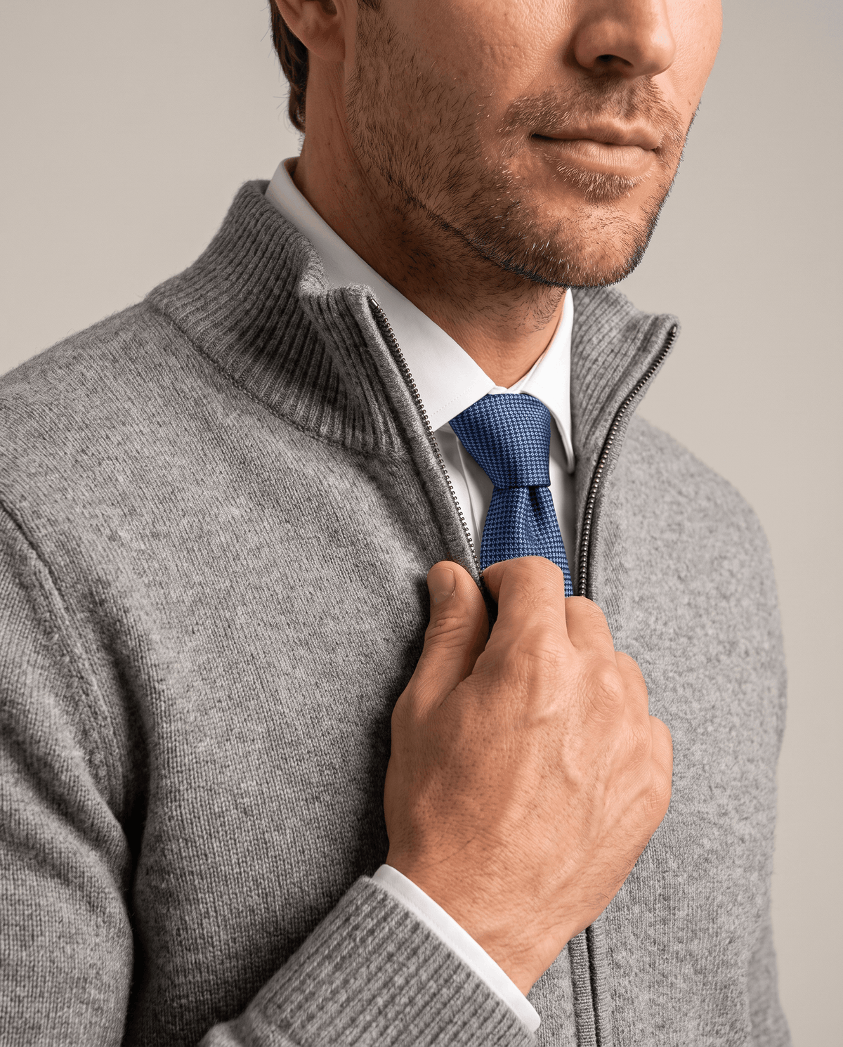 Light gray cardigan with stand collar worn over a white shirt and navy tie
