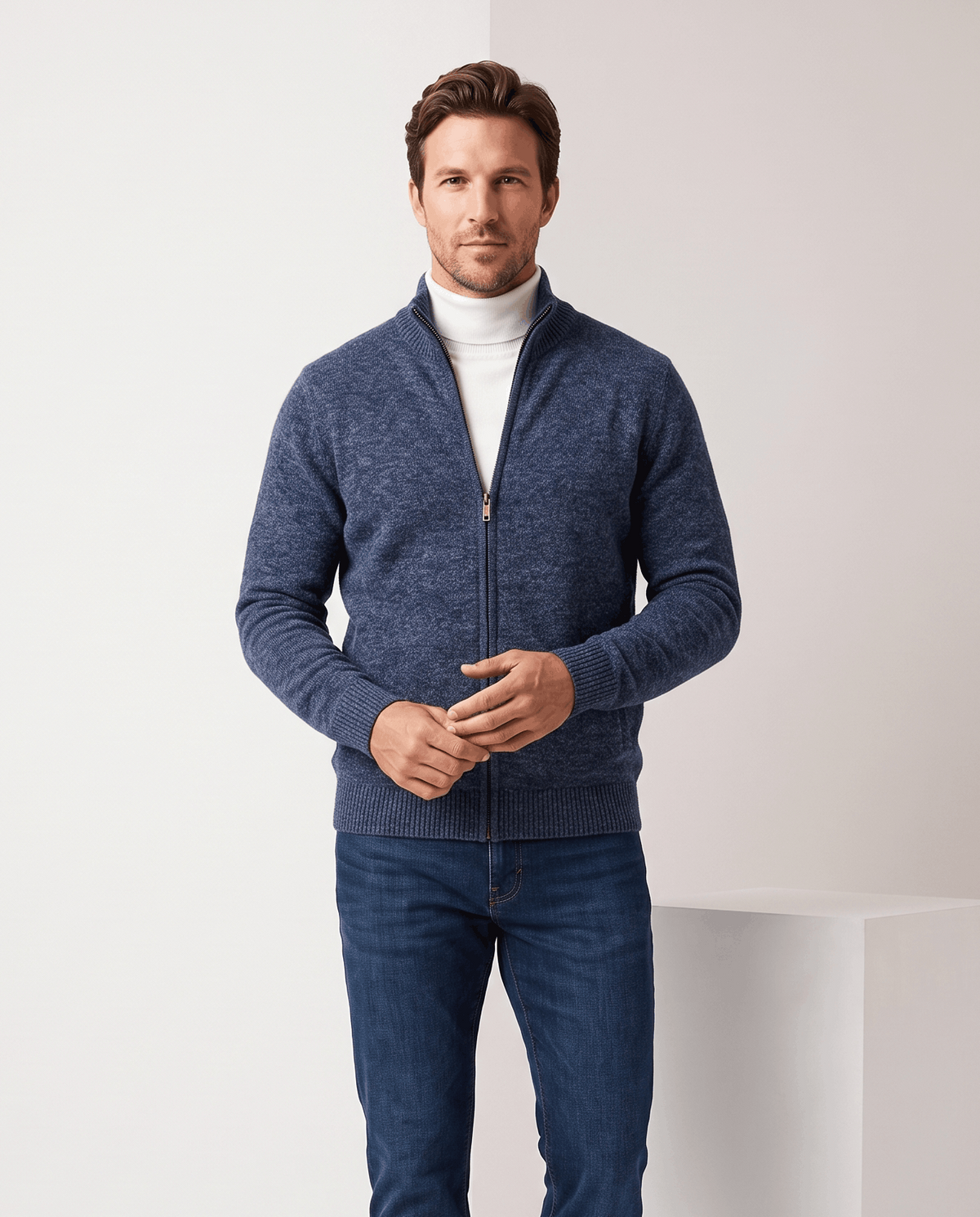 Navy zip-up cardigan worn open over a white turtleneck with blue jeans