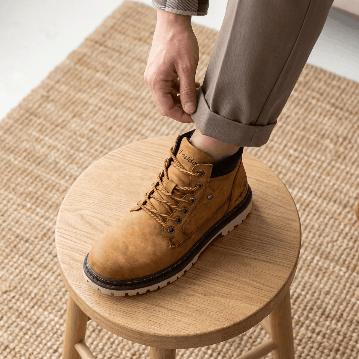 Brown textured grain lace-up work boot with a stitched welt, chunky lug outsole, and padded collar resting on a wooden stool.