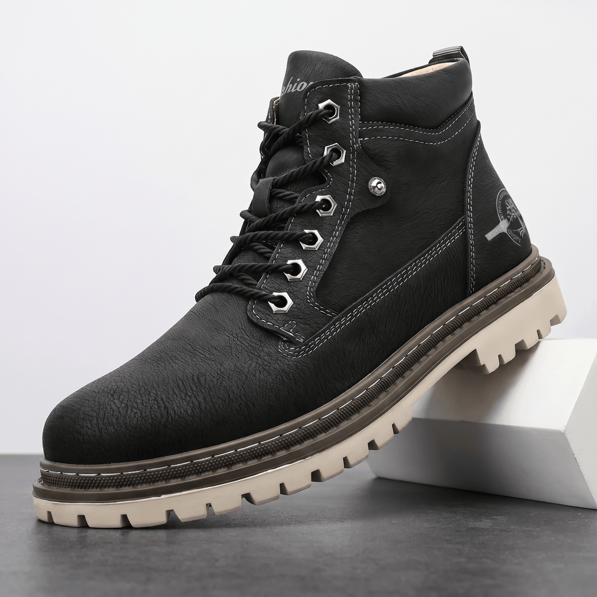 Black matte textured leather work boot with a stitched welt, bolt-style hex eyelets, and a chunky beige lug outsole.
