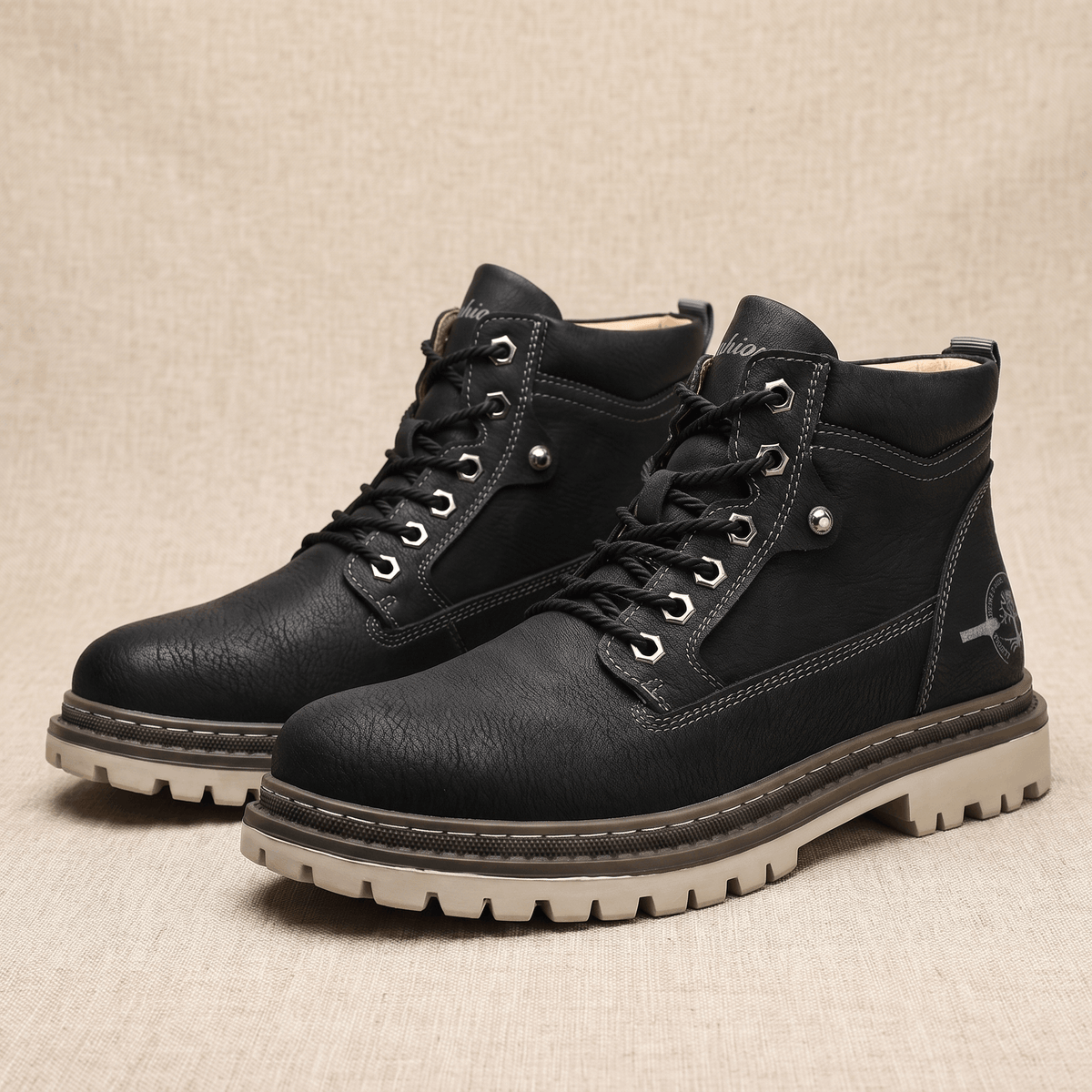 Black textured grain leather work boots with a stitched welt, padded ankle collar, and silver bolt-style hex eyelets.