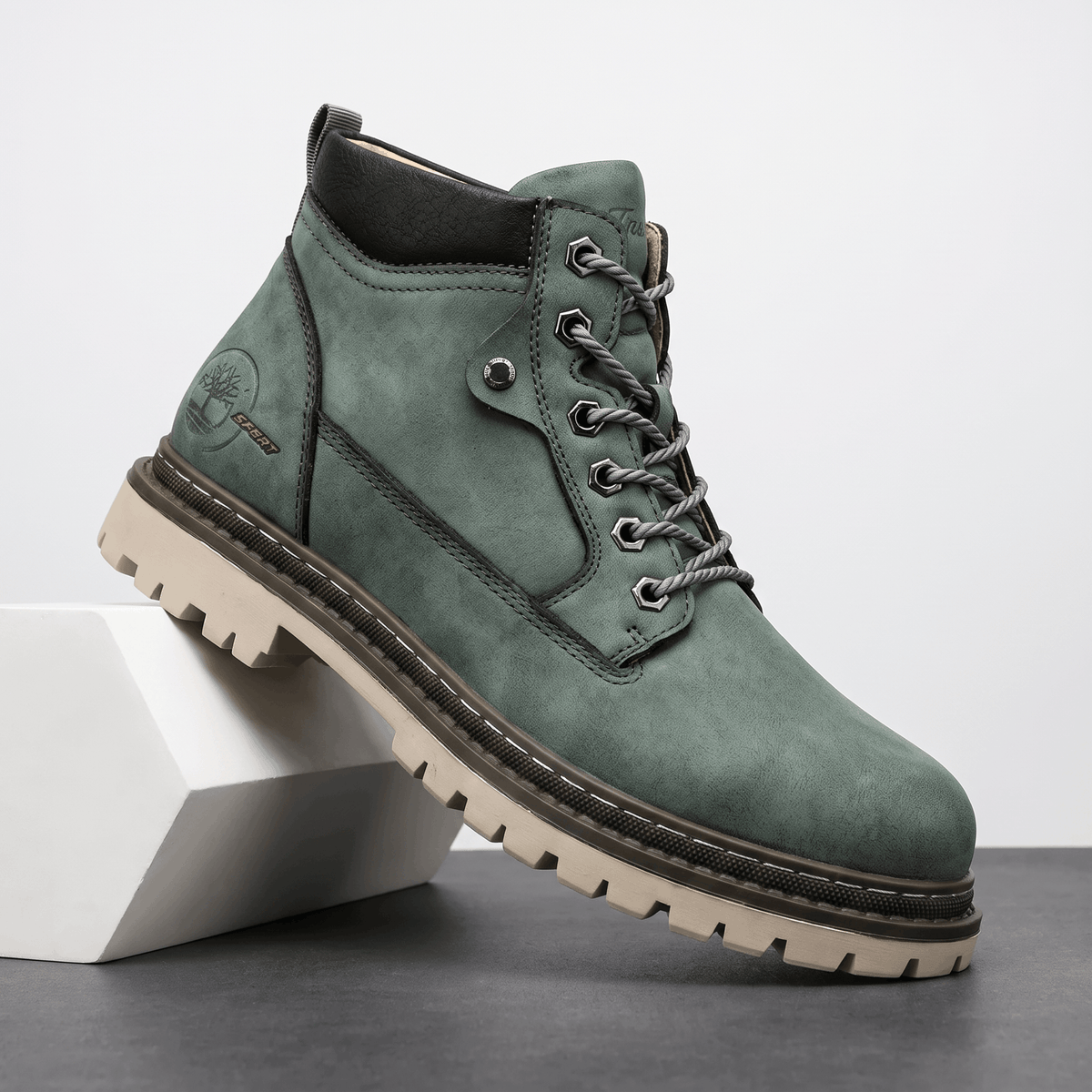 Sage green textured grain lace-up work boot with a black padded collar, bolt-style hex eyelets, and a chunky lug outsole.