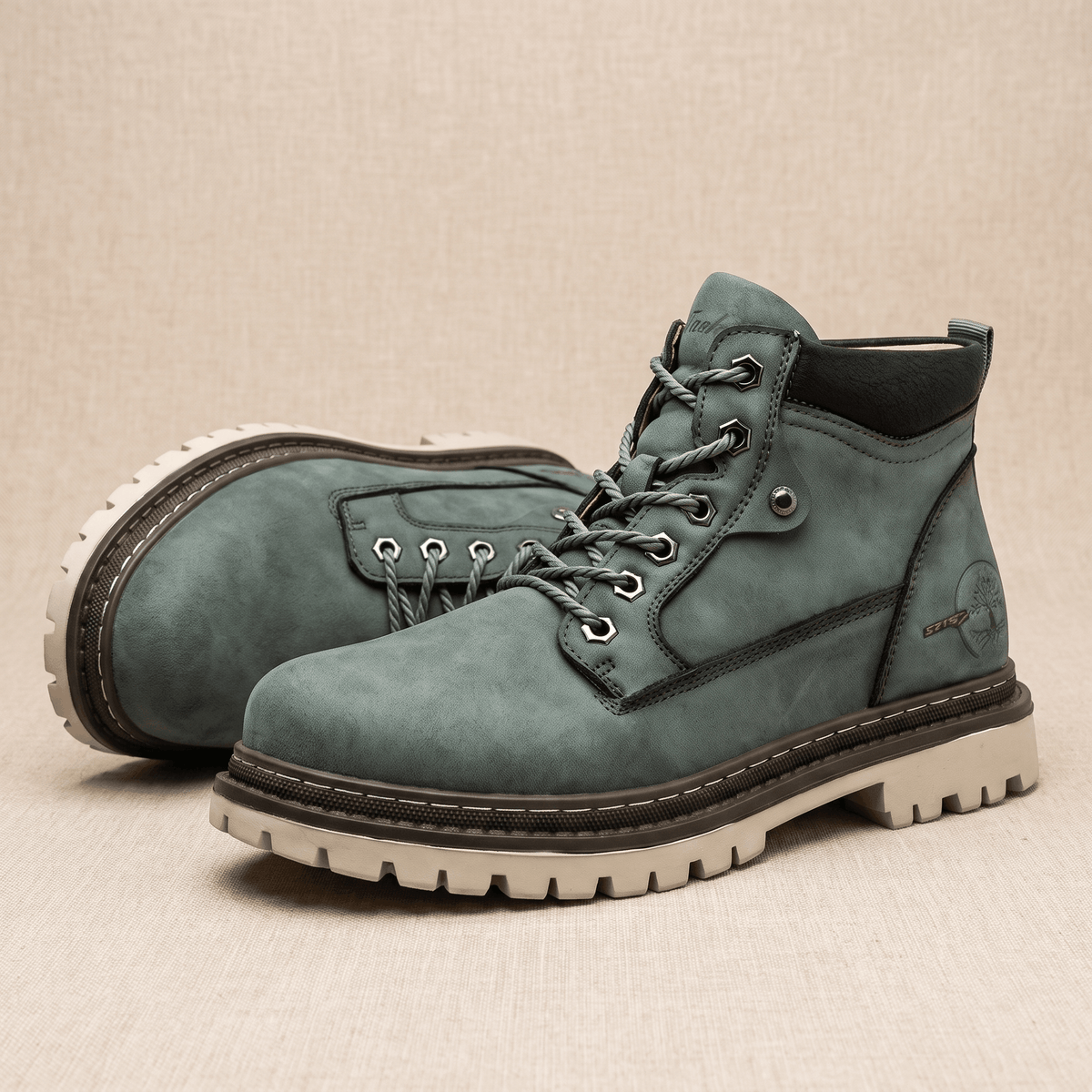 Matte sage green lace-up work boots with a stitched welt, chunky lug sole, padded black ankle collar, and reinforced hex eyelets.