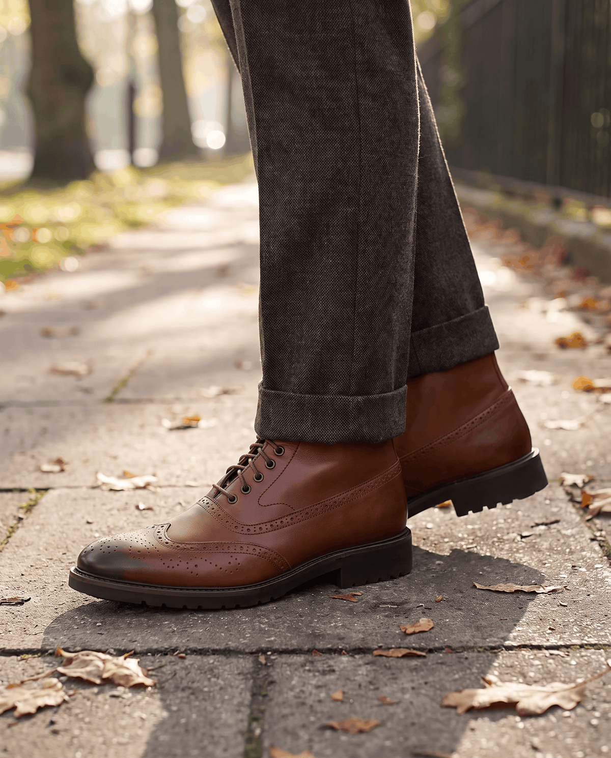 Man walking on a paved autumn street in brown leather ankle boots and dark trousers