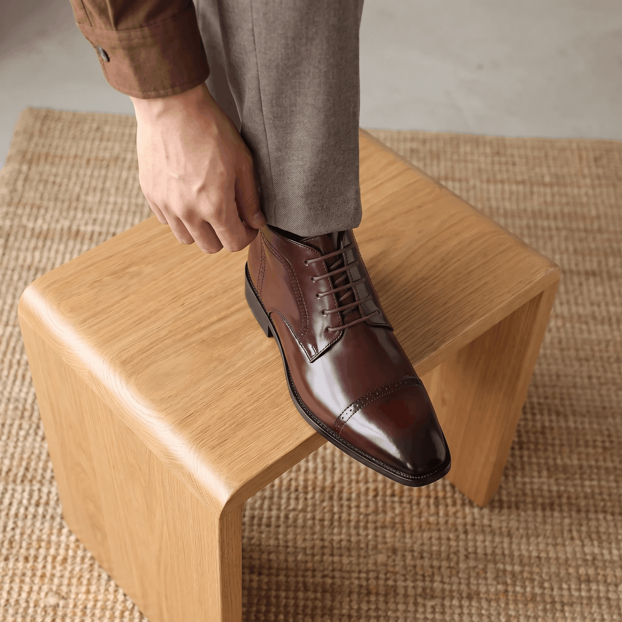 Polished dark brown leather brogue boots with a punched cap toe, five-eyelet lacing, and a slim non-slip rubber sole.