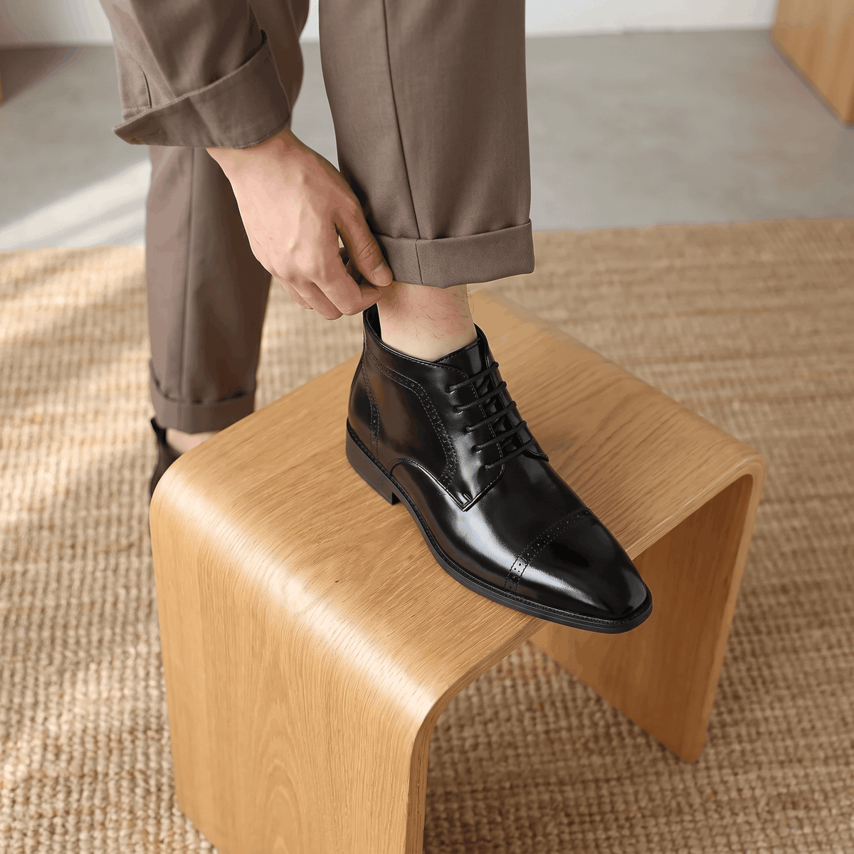 Polished black leather brogue boots featuring a punched cap toe, five-eyelet lacing, and a slim non-slip rubber sole.