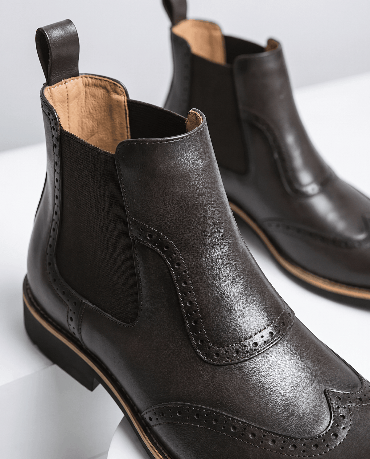 Close-up of a dark brown boot showing the elastic panel and tan leather lining