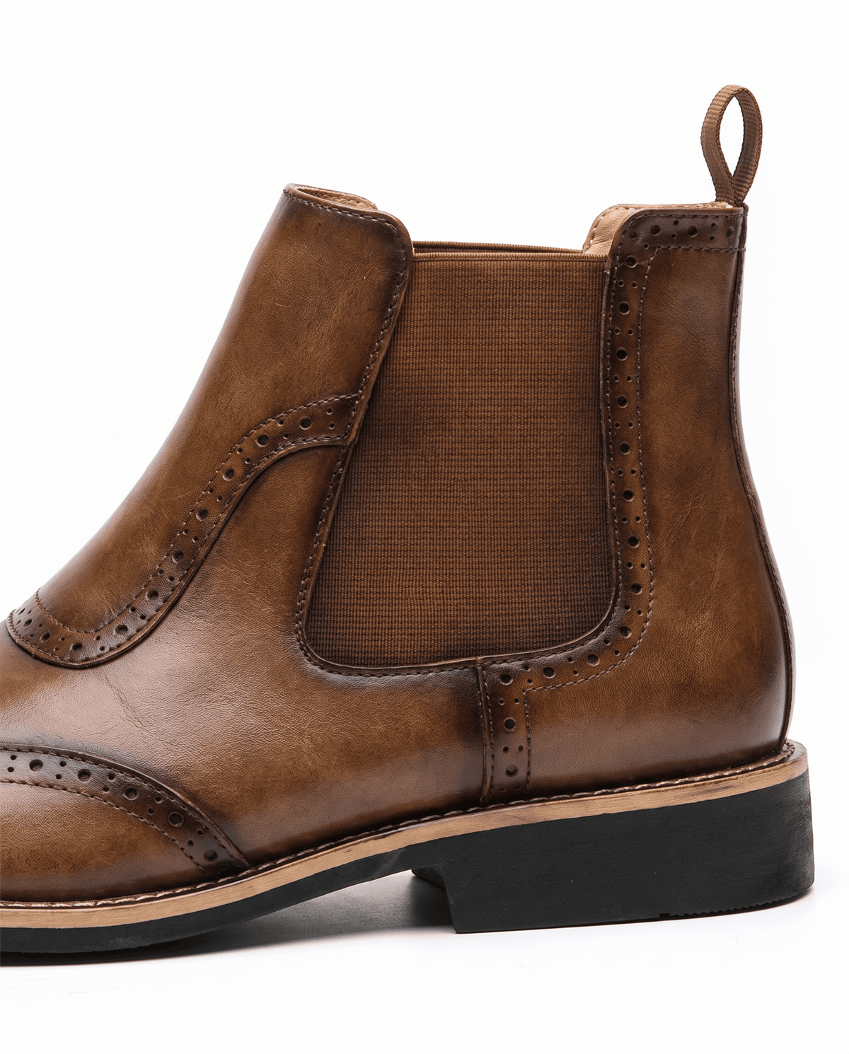 Close-up of a tan Chelsea boot showing the pull tab, elastic panel and rubber sole