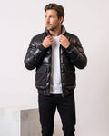 Man wearing the black leather-look puffer bomber, holding the sherpa-lined stand collar
