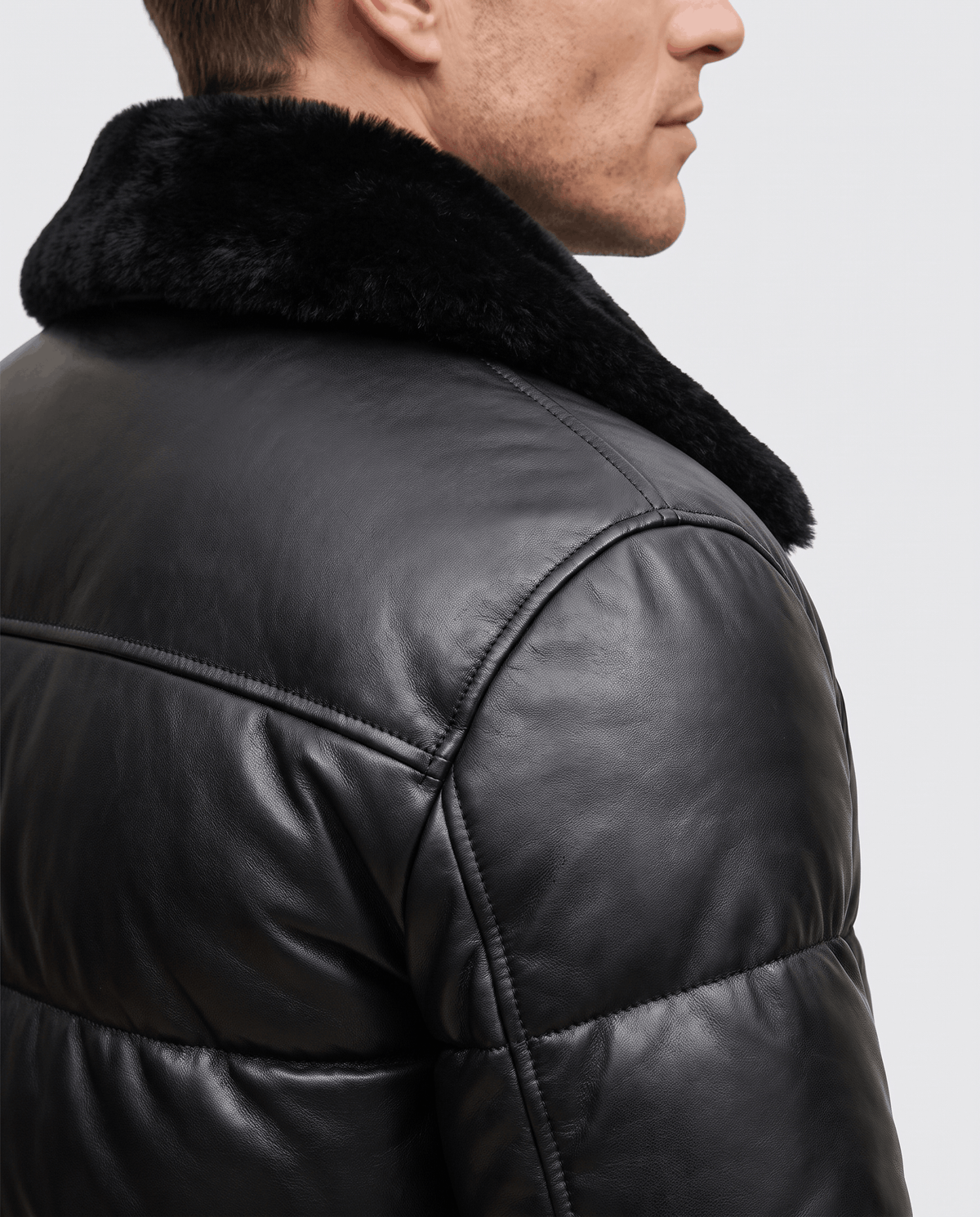 Detail of black shearling-look fold-over collar against smooth quilted shoulder panel