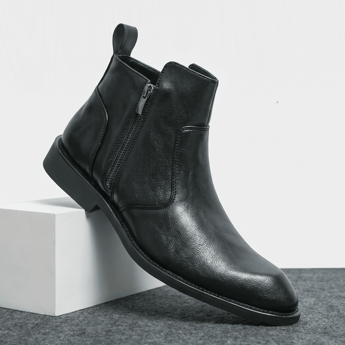 Burnished black leather dress boot with a pointed toe, inside zip closure, and a slim stacked block heel.