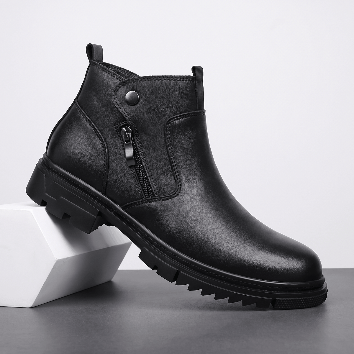 Black leather ankle boot with side zip, snap tab detail, and a chunky lugged rubber outsole on a squared block heel.