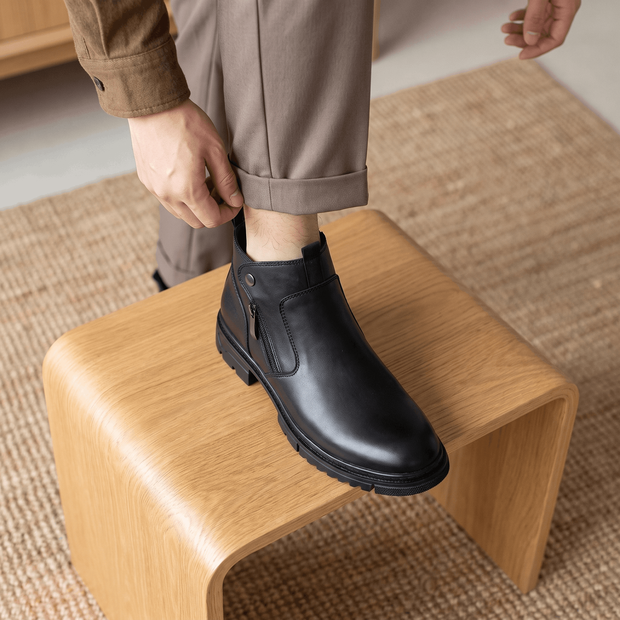Smooth black leather ankle boots with a side zip, snap tab, and chunky lugged rubber outsole.