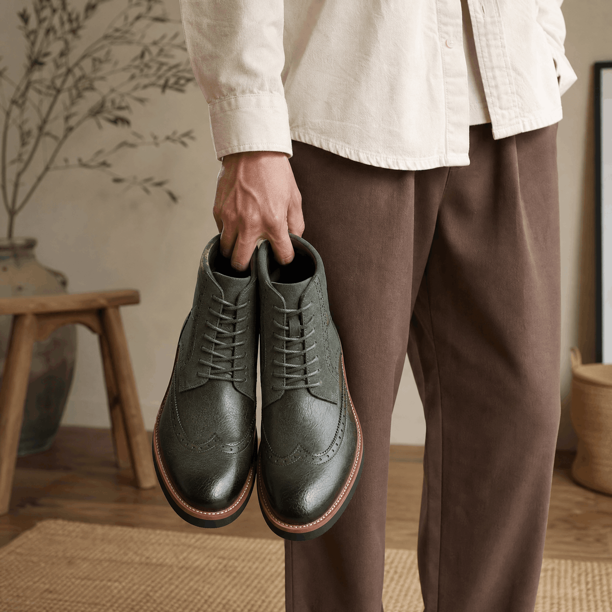 Dark gray leather wingtip ankle boots with suede shaft panels, burnished toes, and welted rubber soles held by hand.