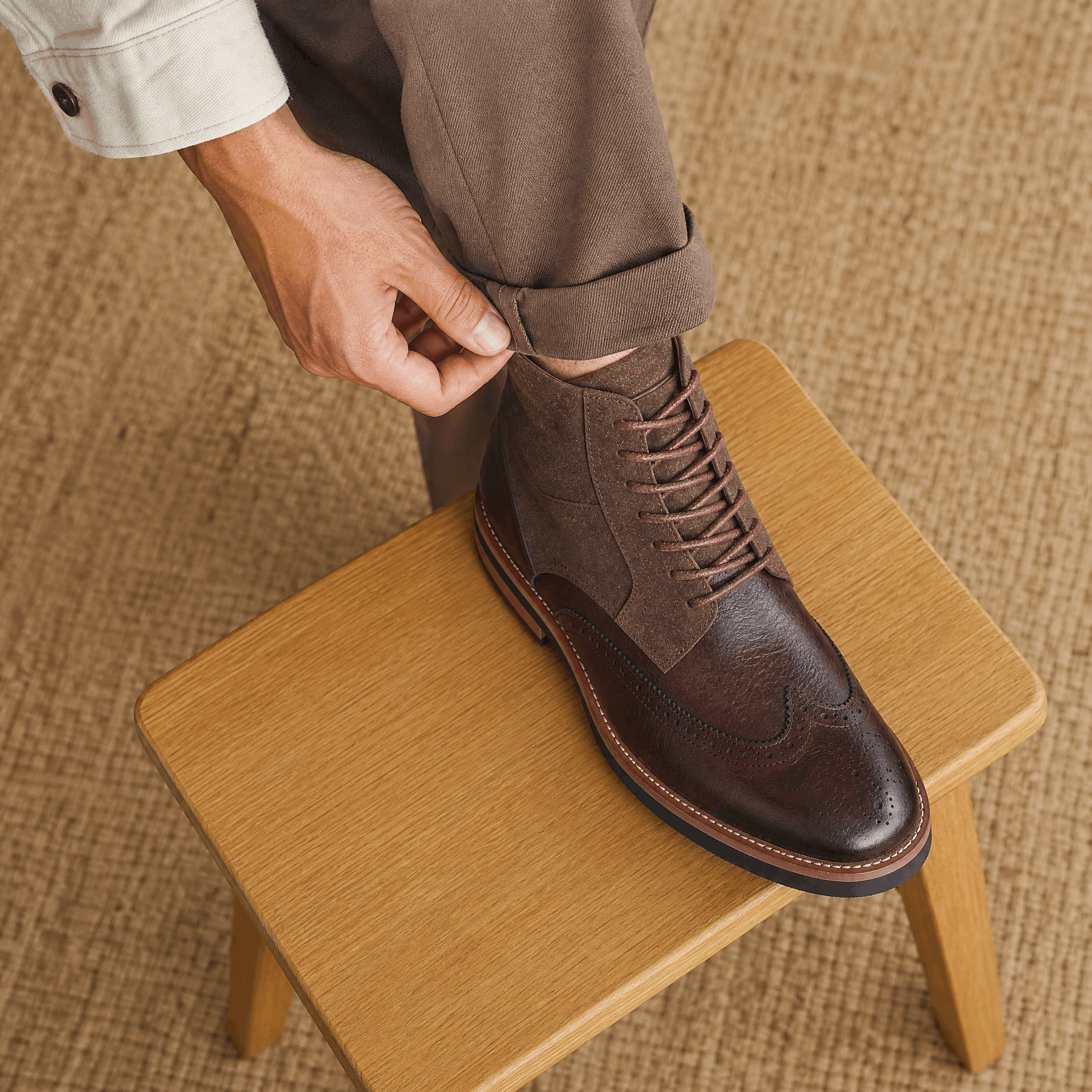 Dark brown leather wingtip brogue ankle boots with a suede shaft panel, lace-up closure, and a durable welted rubber sole.