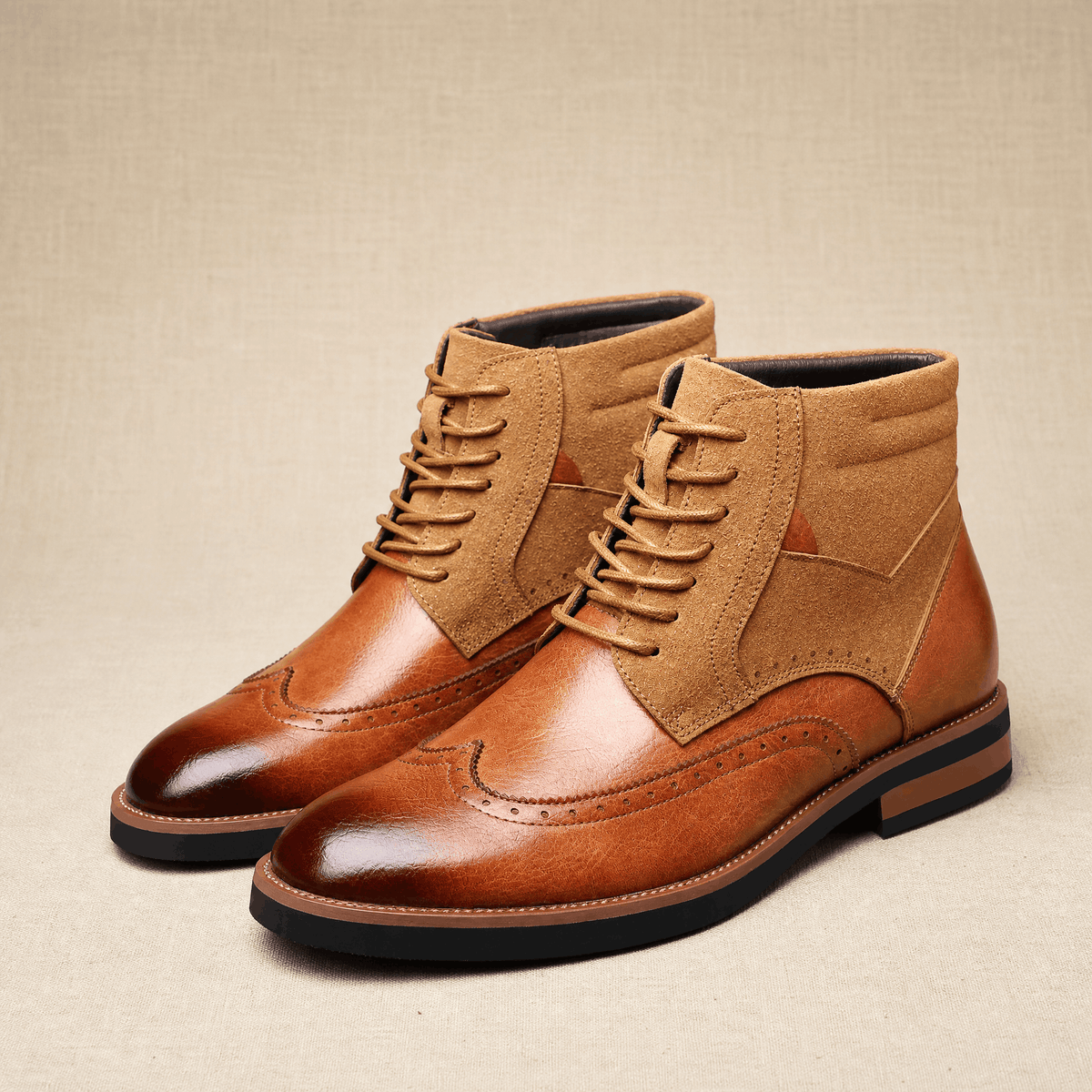 Tan leather wingtip ankle boots with burnished toes, suede shaft panels, and a sturdy welted rubber sole.