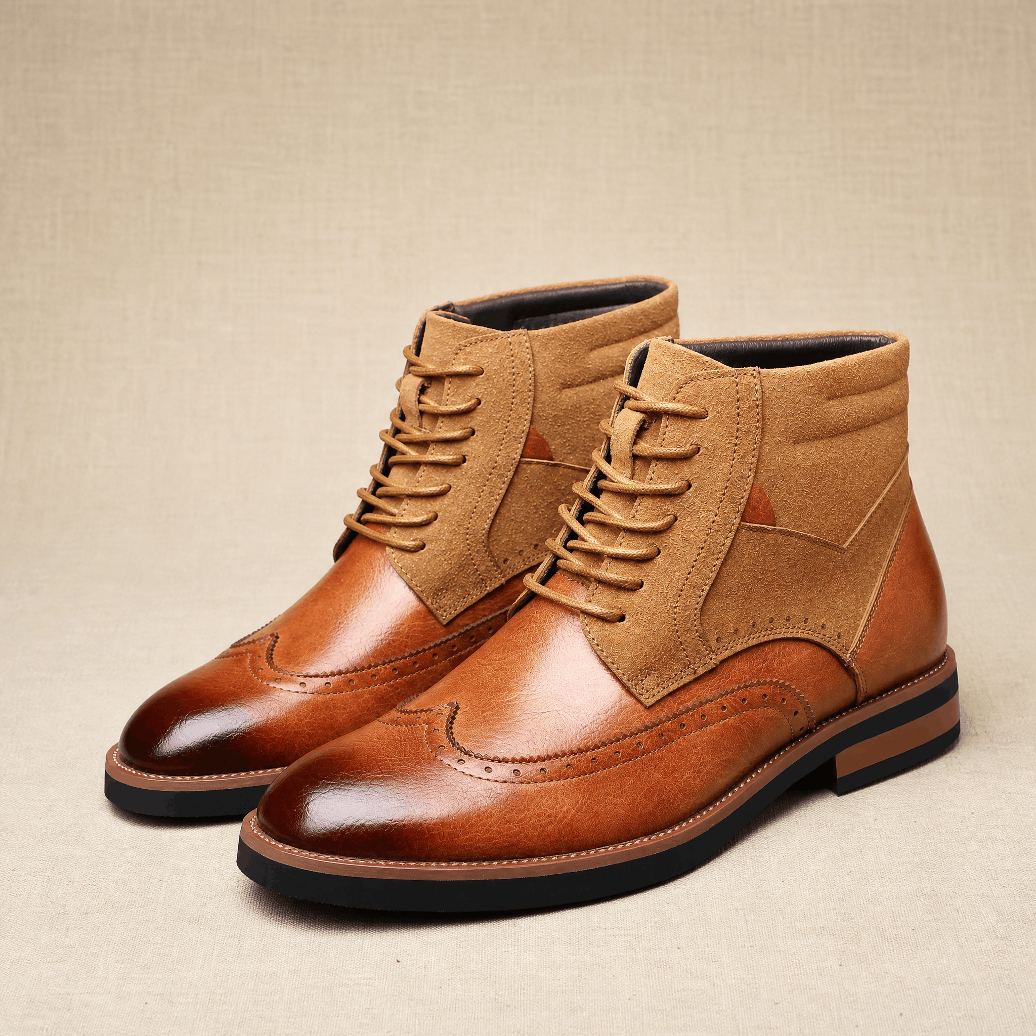 Tan leather wingtip ankle boots with burnished toes, suede shaft panels, and a sturdy welted rubber sole.