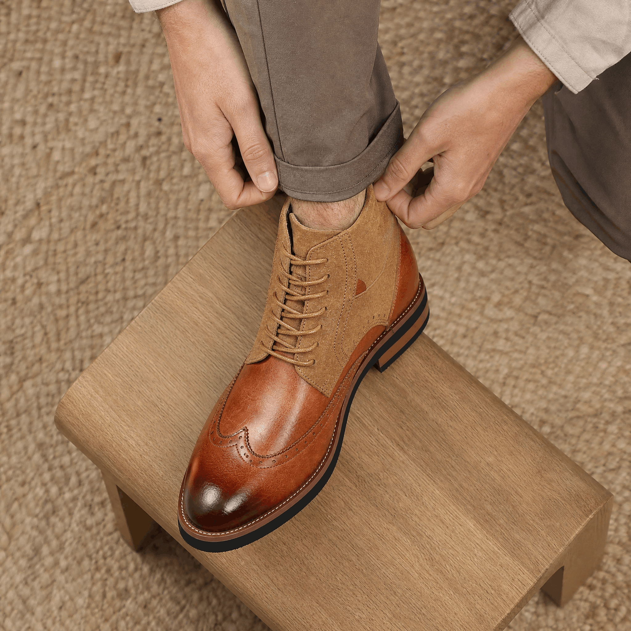 Tan leather wingtip brogue ankle boots featuring a suede shaft, burnished toe cap, and a sturdy welted rubber sole.