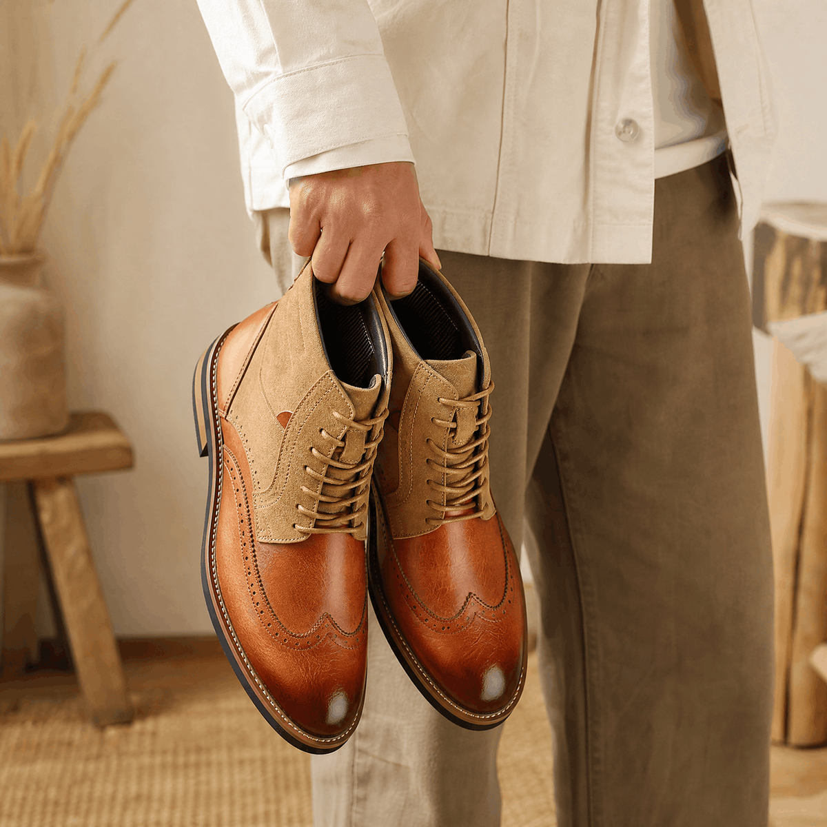 Tan leather wingtip brogue ankle boots with suede shafts, burnished toes, and treaded rubber welted soles.