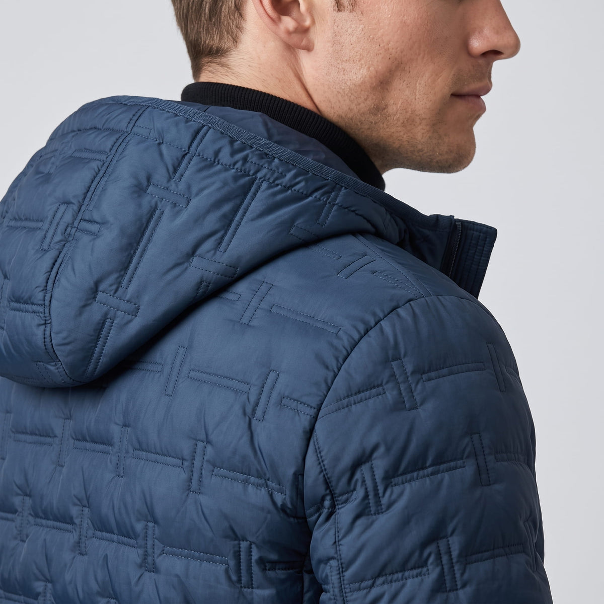 Close view of the navy hood and shoulder, showing quilted block seams