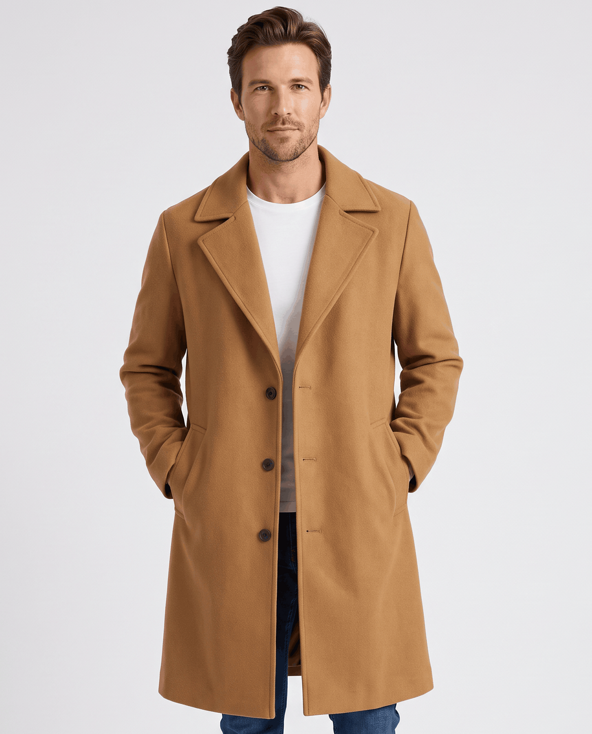 Brown longline coat worn buttoned over a white tee and jeans, hands in pockets, front view