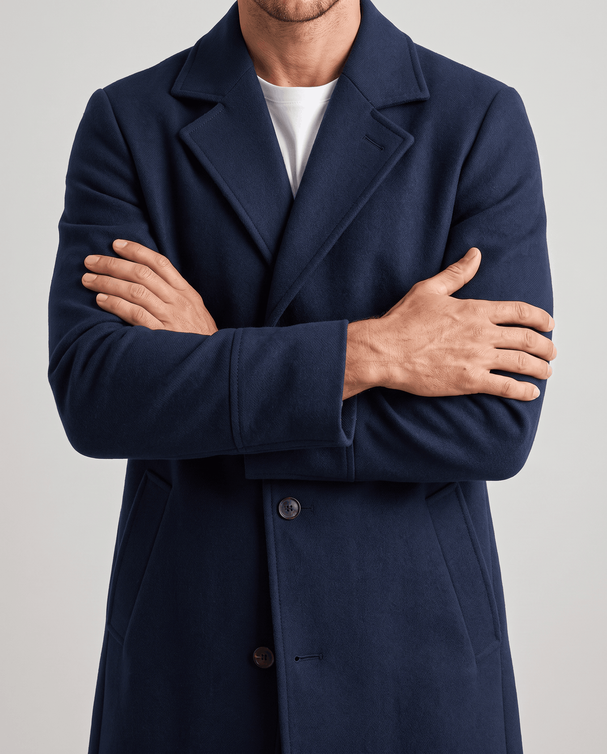 Navy coat close-up with arms crossed, showing the notch lapel and front buttons