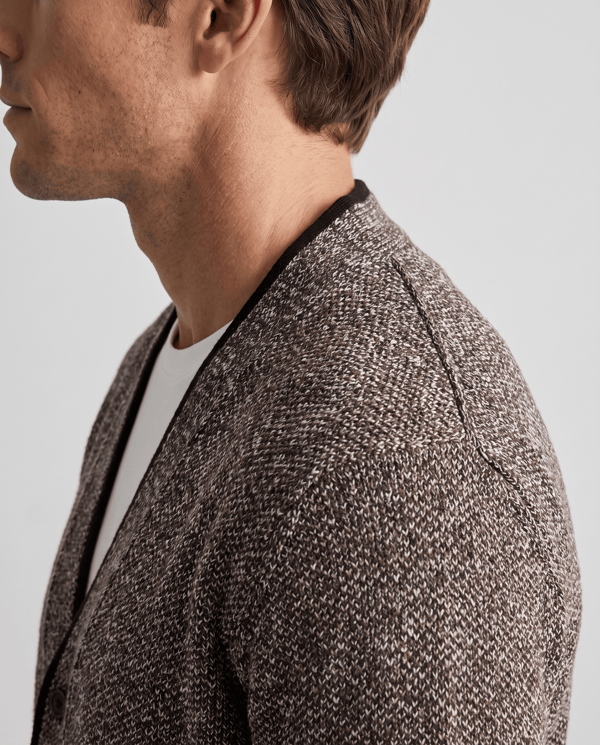Side close-up of the brown cardigan black V-neck trim over a white tee