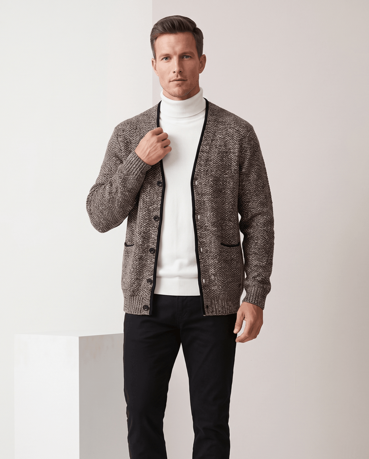 Brown marled cardigan with black trim worn over a white turtleneck and black trousers