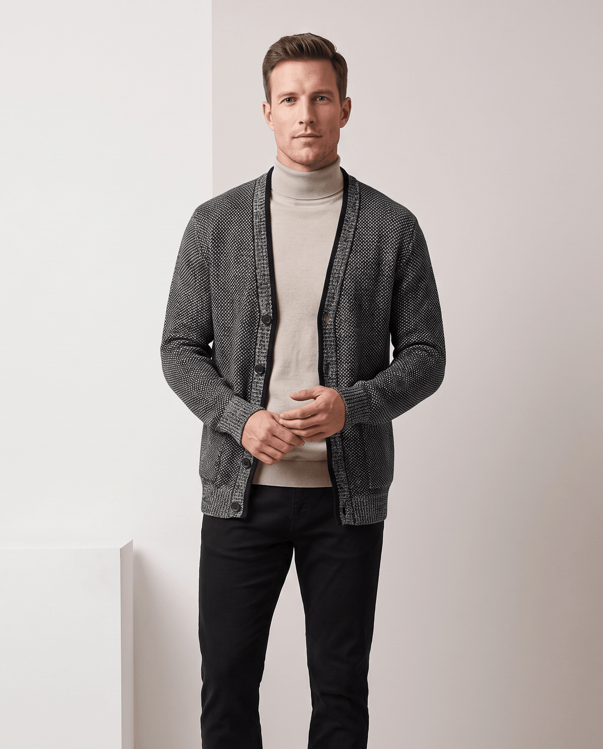 Dark gray marled cardigan worn over a beige turtleneck with black trousers