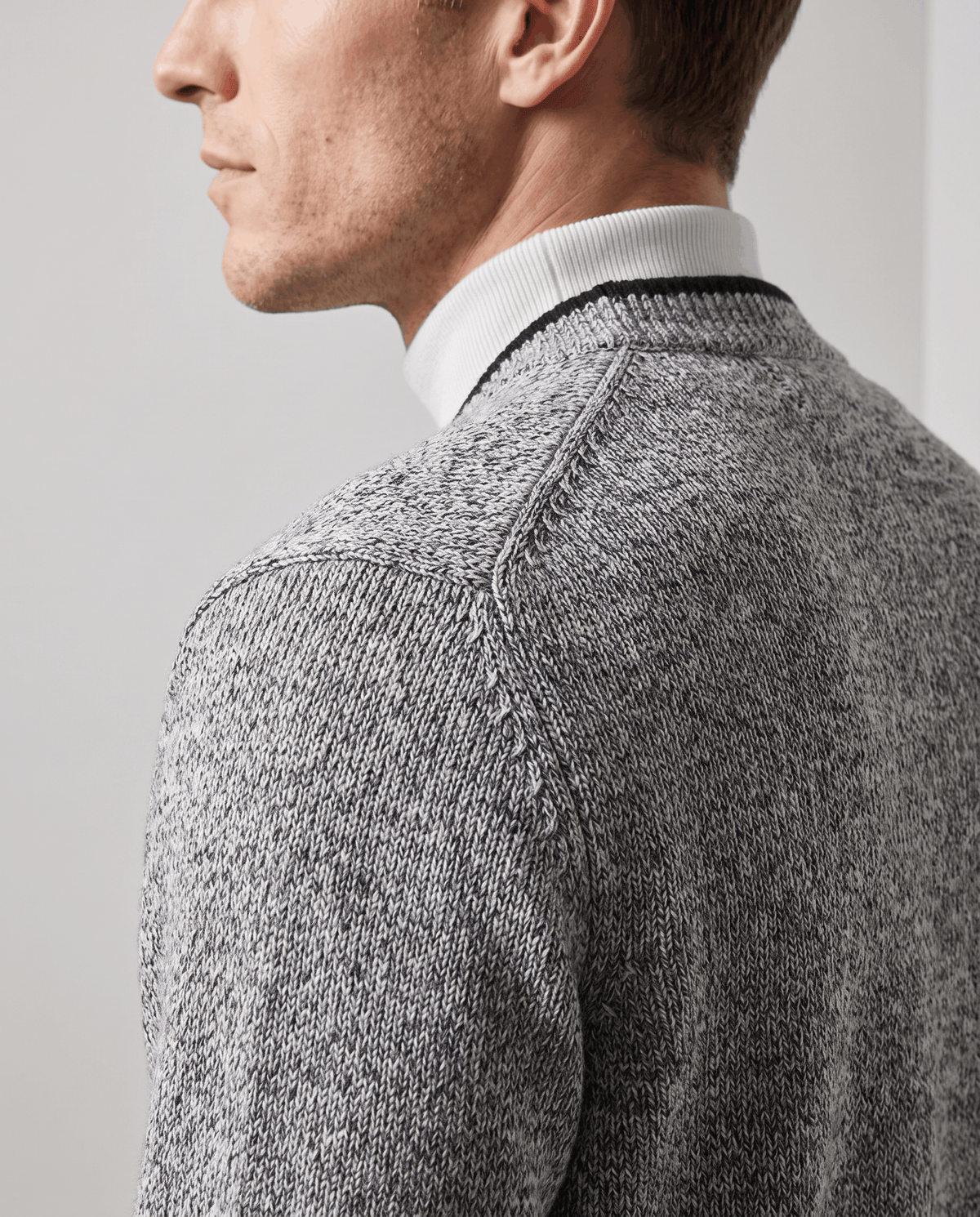 Side profile of the light gray cardigan V-neck trim over a white turtleneck